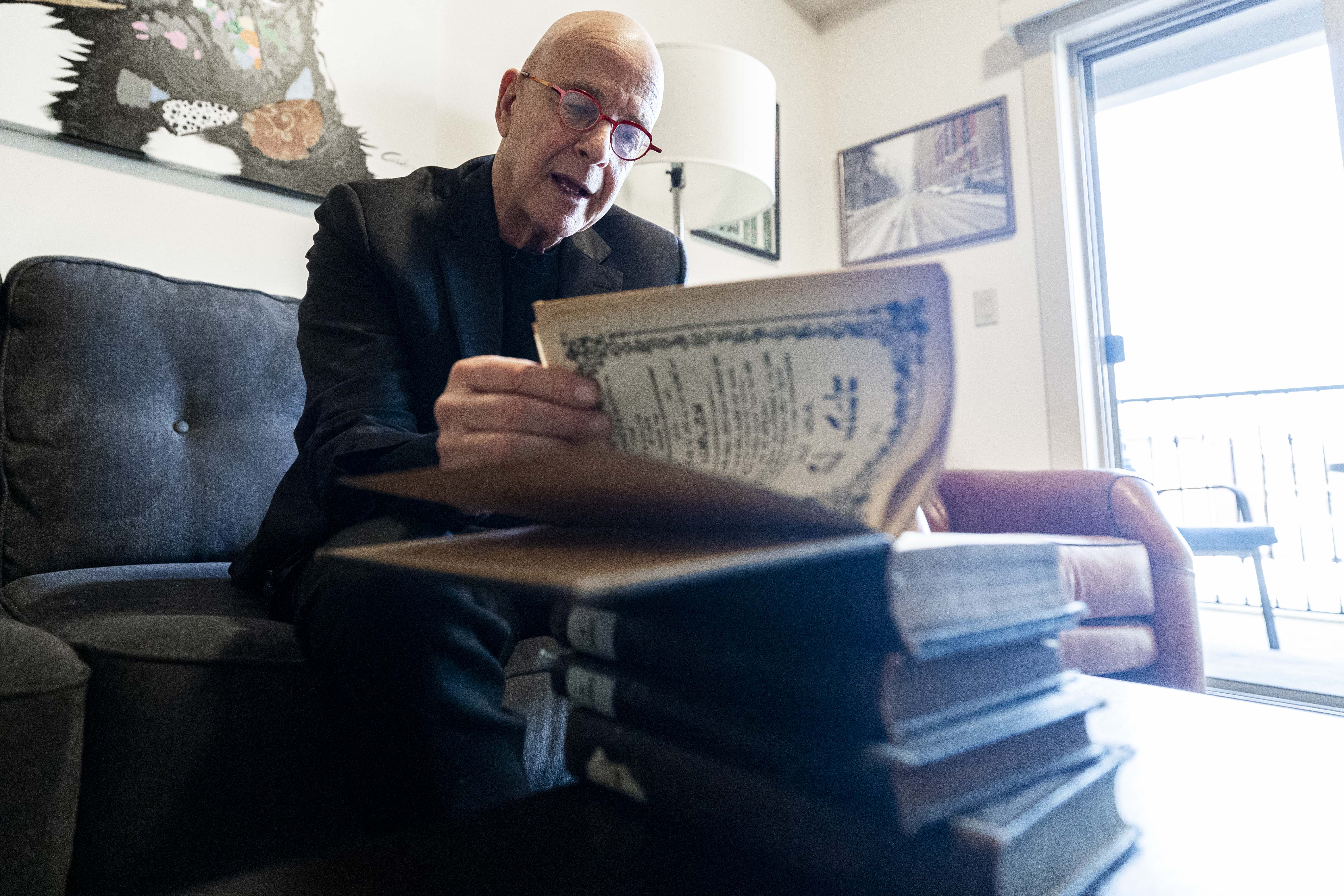 Amos Guiora flips through a book that was taken by Nazis from his Jewish grandfather during World War II as Guiora is interviewed at his home in Salt Lake City on Monday.