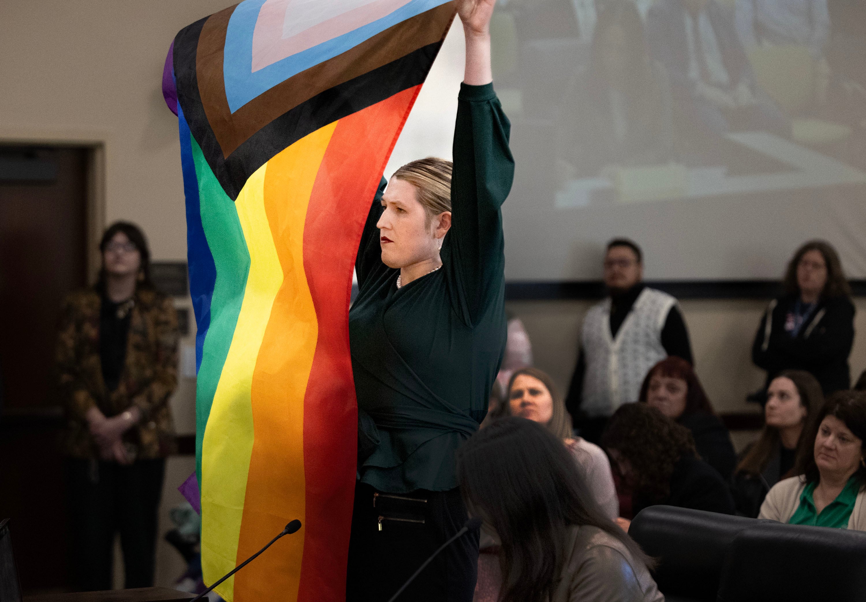 Charlotte Weber displays a pride flag while speaking in opposition to HB77, Flag Display Amendments, in a Senate Education Committee meeting at the Capitol in Salt Lake City on Friday.