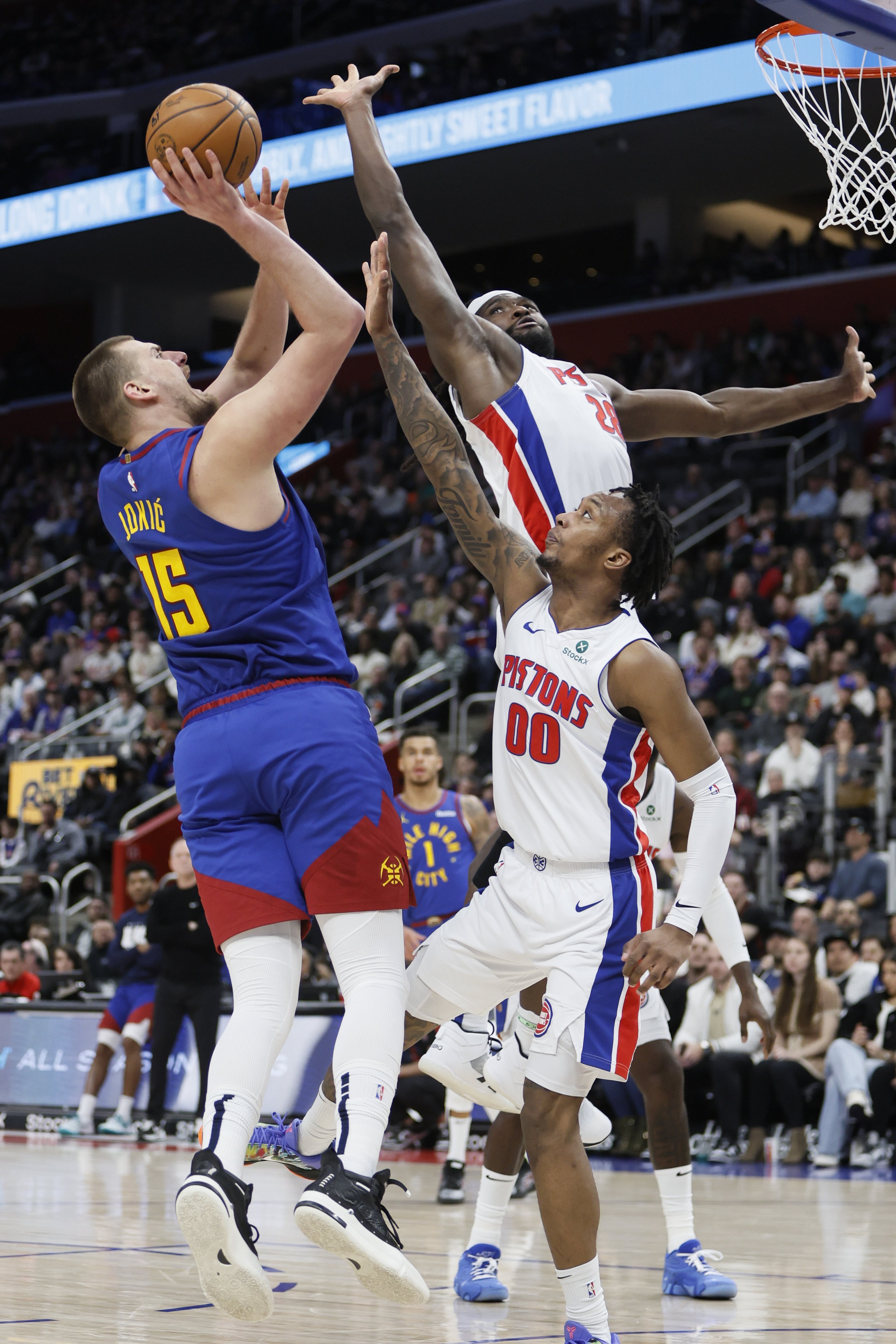 Denver Nuggets center Nikola Jokic (15) is guarded by Detroit Pistons center Isaiah Stewart (28) and forward Ronald Holland II (00) while taking a shot during the first half of an NBA basketball game Friday, Feb. 28, 2025, in Detroit. 
