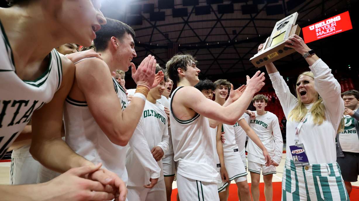 Olympus High School principal Jen Christensen hands the 5A boys state trophy to Olympus' Gavin Lowe, middle, and his teammates after winning the 5A boys state basketball championship game against Highland at the Huntsman Center in Salt Lake City on Friday, Feb. 28, 2025. Olympus won 69-40.