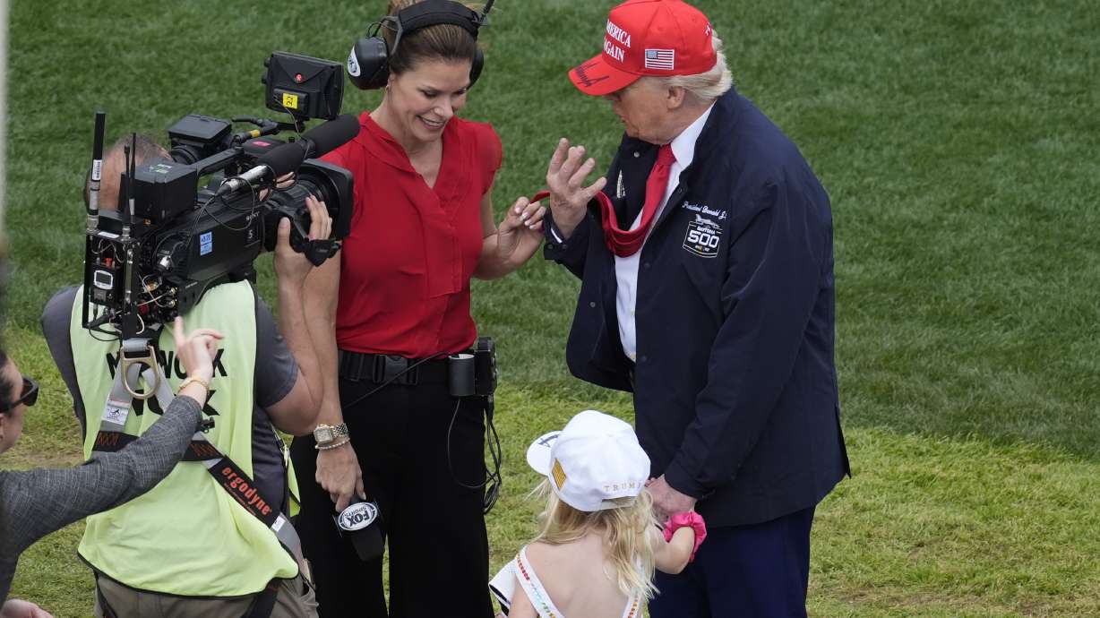 President Donald Trump, right, with granddaughter Carolina, center, speaks during an interview at the NASCAR Daytona 500 auto race at Daytona International Speedway, Sunday, Feb. 16, 2025, in Daytona Beach, Fla.