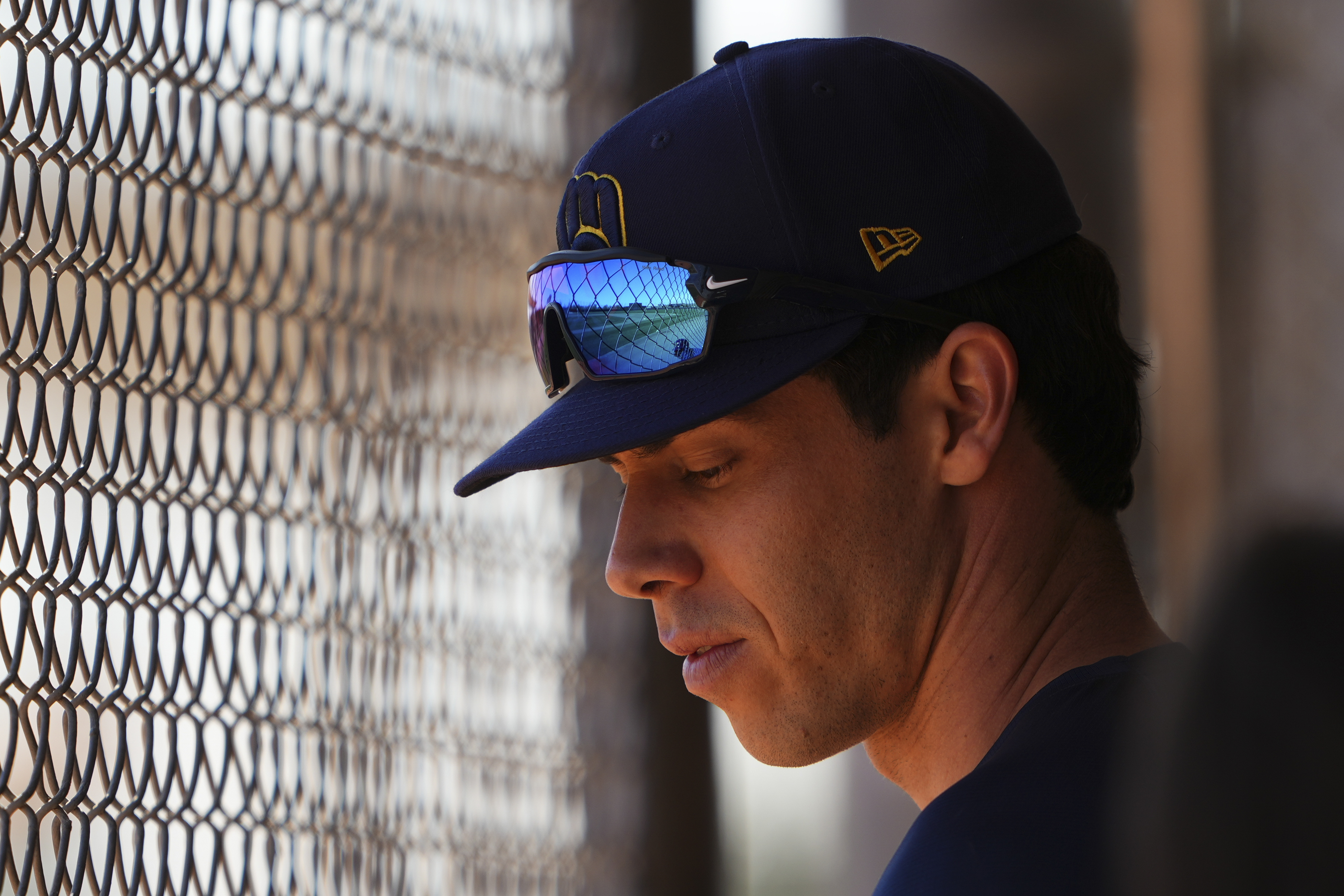 Milwaukee Brewers left fielder Christian Yelich looks down in a dugout as teammates take live batting practice during spring training baseball practice at the team's training facility Friday, Feb. 21, 2025, in Phoenix. 