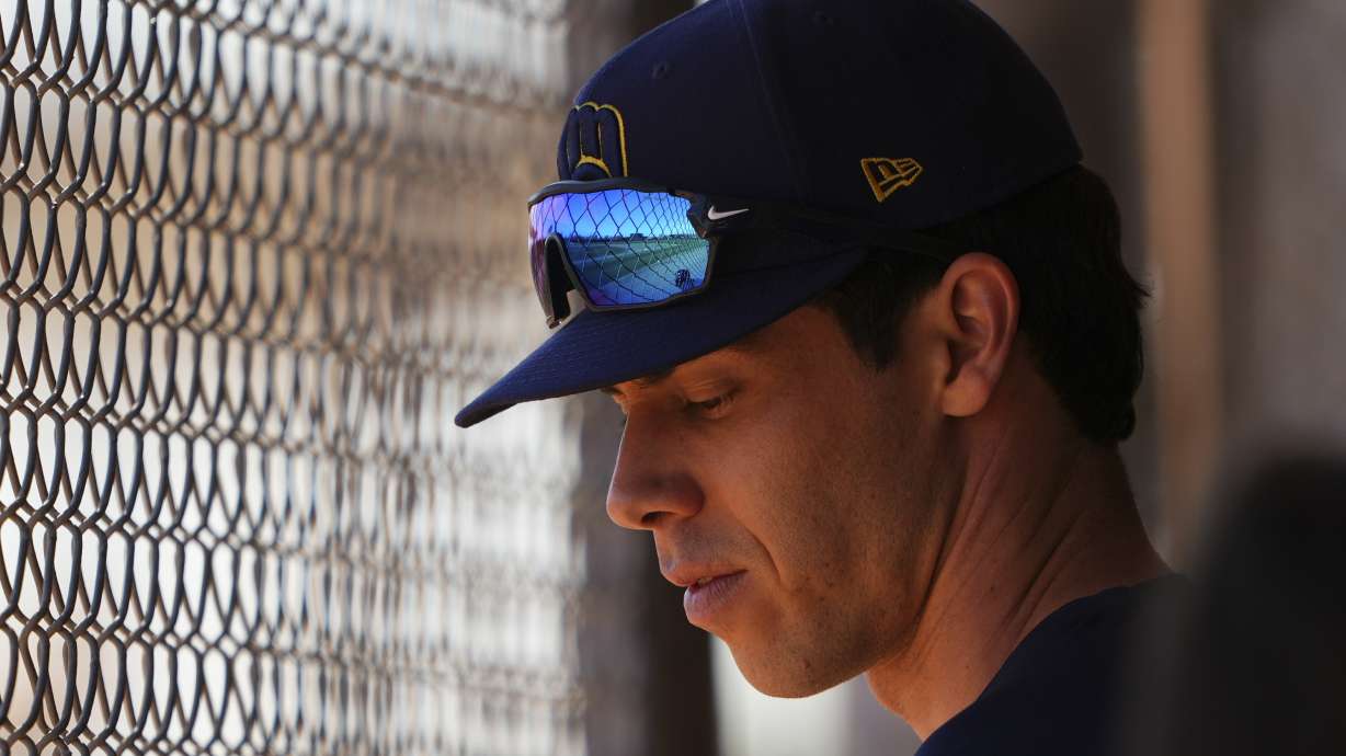 Milwaukee Brewers left fielder Christian Yelich looks down in a dugout as teammates take live batting practice during spring training baseball practice at the team's training facility Friday, Feb. 21, 2025, in Phoenix.