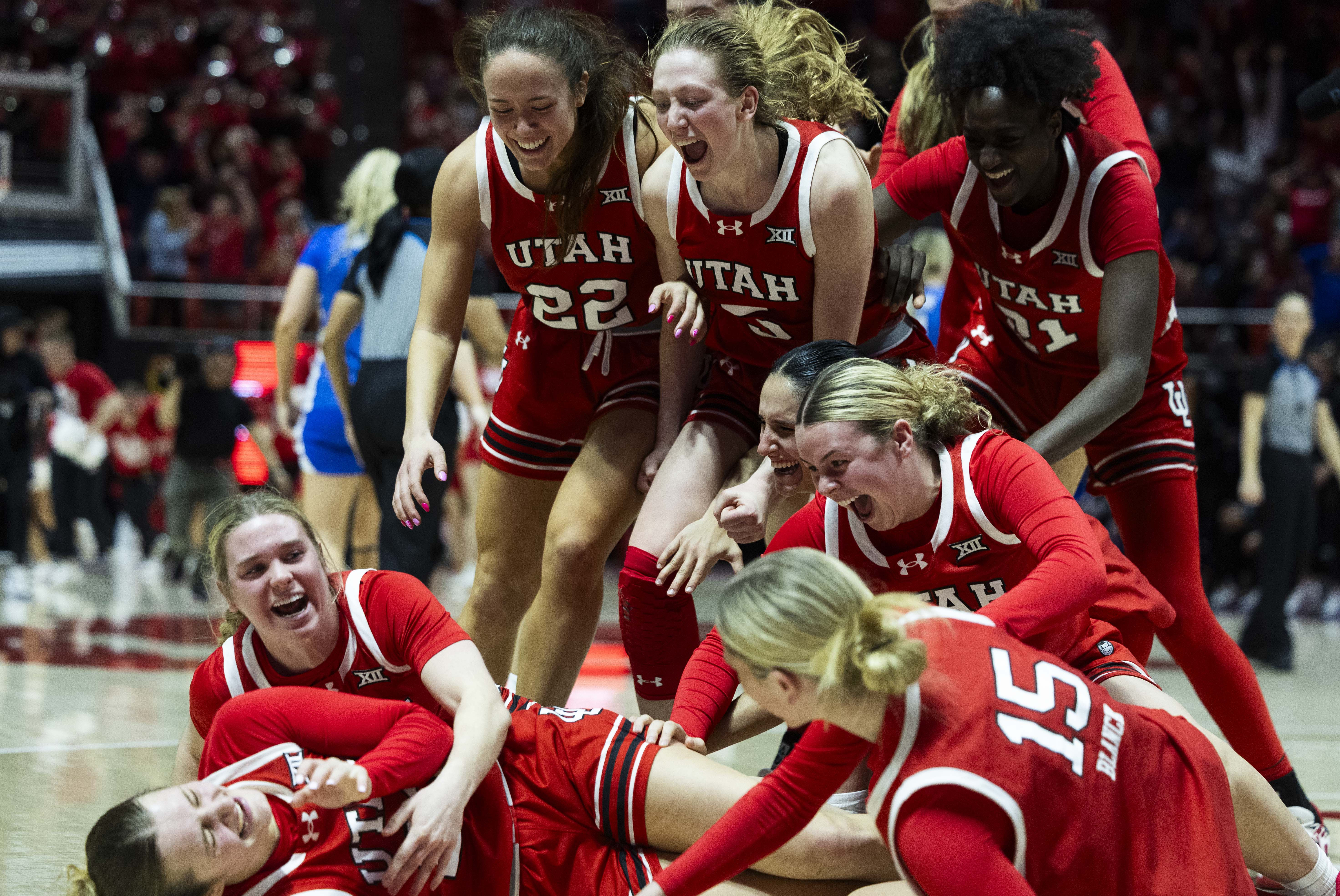 Utah Utes players rush to celebrate with guard Matyson Wilke (23), bottom left, after she made a buzzer beater to win the game against BYU in overtime during a Women’s NCAA basketball game at the Jon M. Huntsman Center on the campus of the University of Utah in Salt Lake City on Saturday, March 1, 2025.
