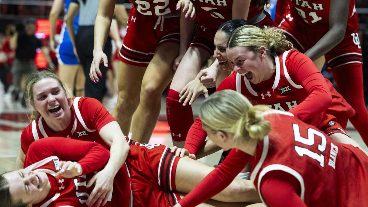 Utah Utes players rush to celebrate with guard Matyson Wilke (23), bottom left, after she made a buzzer beater to win the game against BYU in overtime during a Women’s NCAA basketball game at the Jon M. Huntsman Center on the campus of the University of Utah in Salt Lake City on Saturday, March 1, 2025.