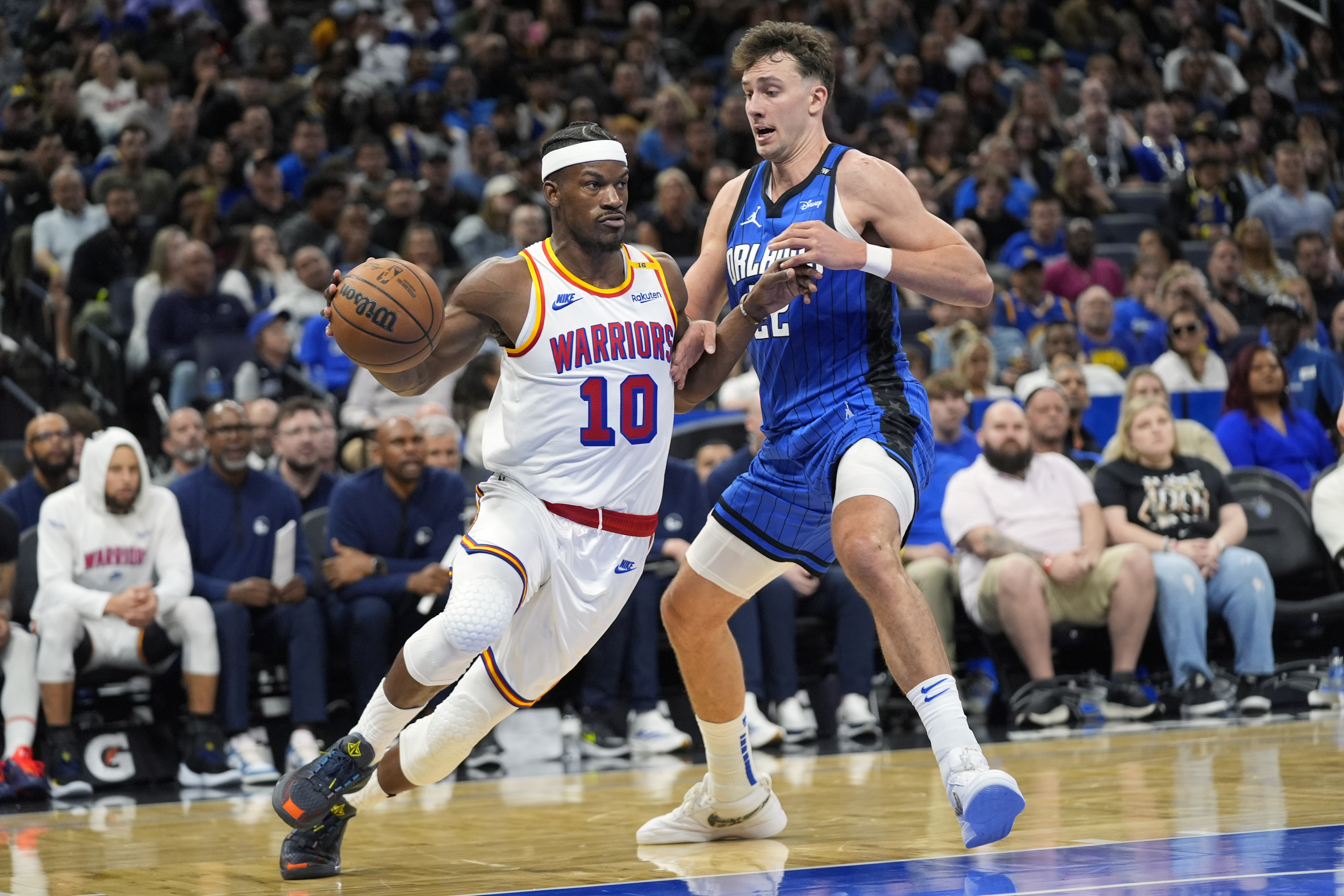 Golden State Warriors forward Jimmy Butler (10) drives past Orlando Magic forward Franz Wagner, right, during the second half of an NBA basketball game, Thursday, Feb. 27, 2025, in Orlando, Fla.