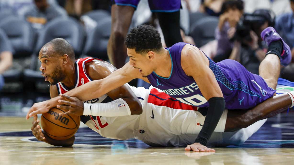 Washington Wizards forward Khris Middleton, left, and Charlotte Hornets guard Josh Green battle for a loose ball during the first half of an NBA basketball game in Charlotte, N.C., Saturday, March 1, 2025.