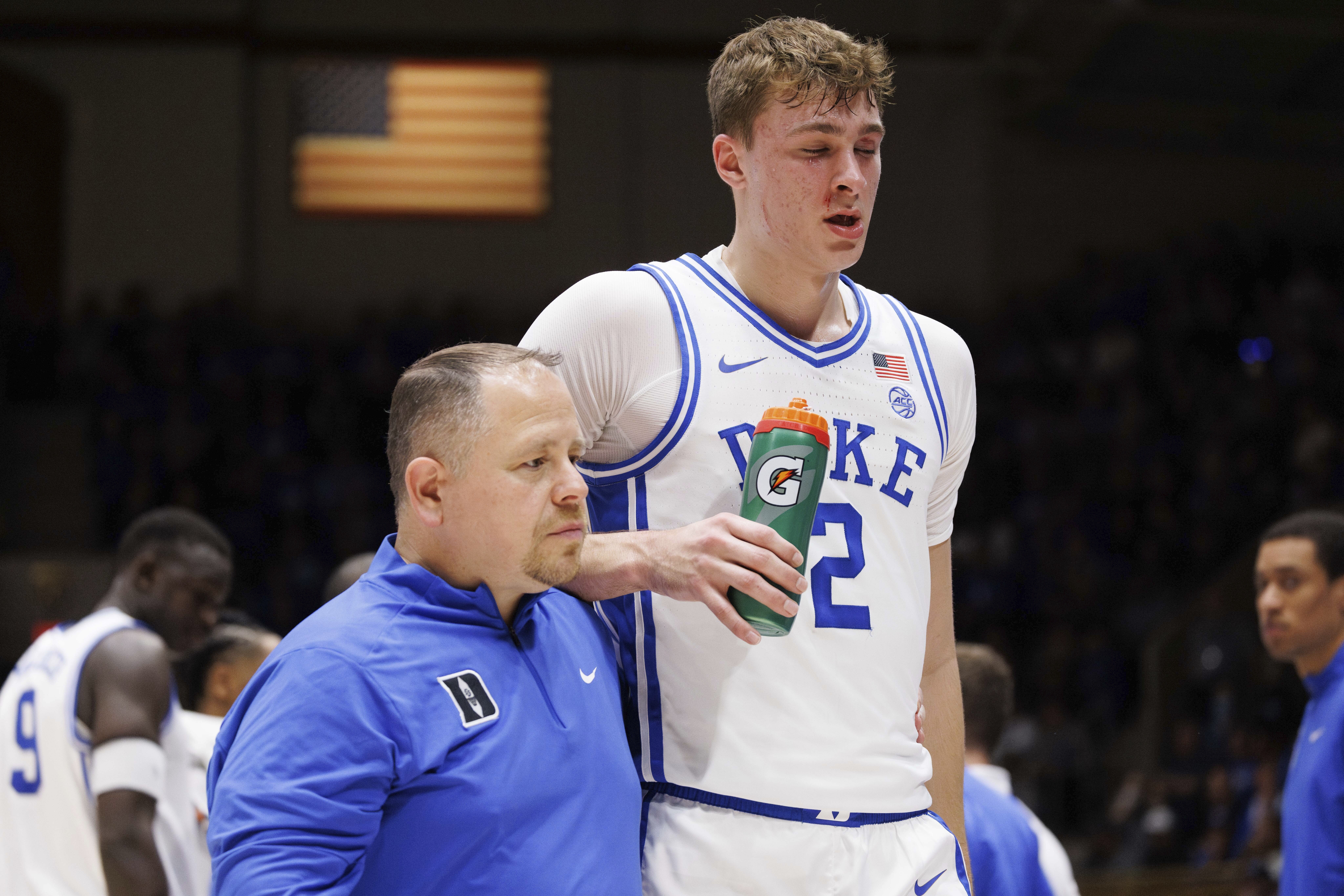 Duke's Cooper Flagg (2) walks off the court with head athletic trainer Jose Fonseca, left, after being accidentally hit in the face in the first half of an NCAA college basketball game against Florida State in Durham, N.C., Saturday, Mar. 1, 2025. 