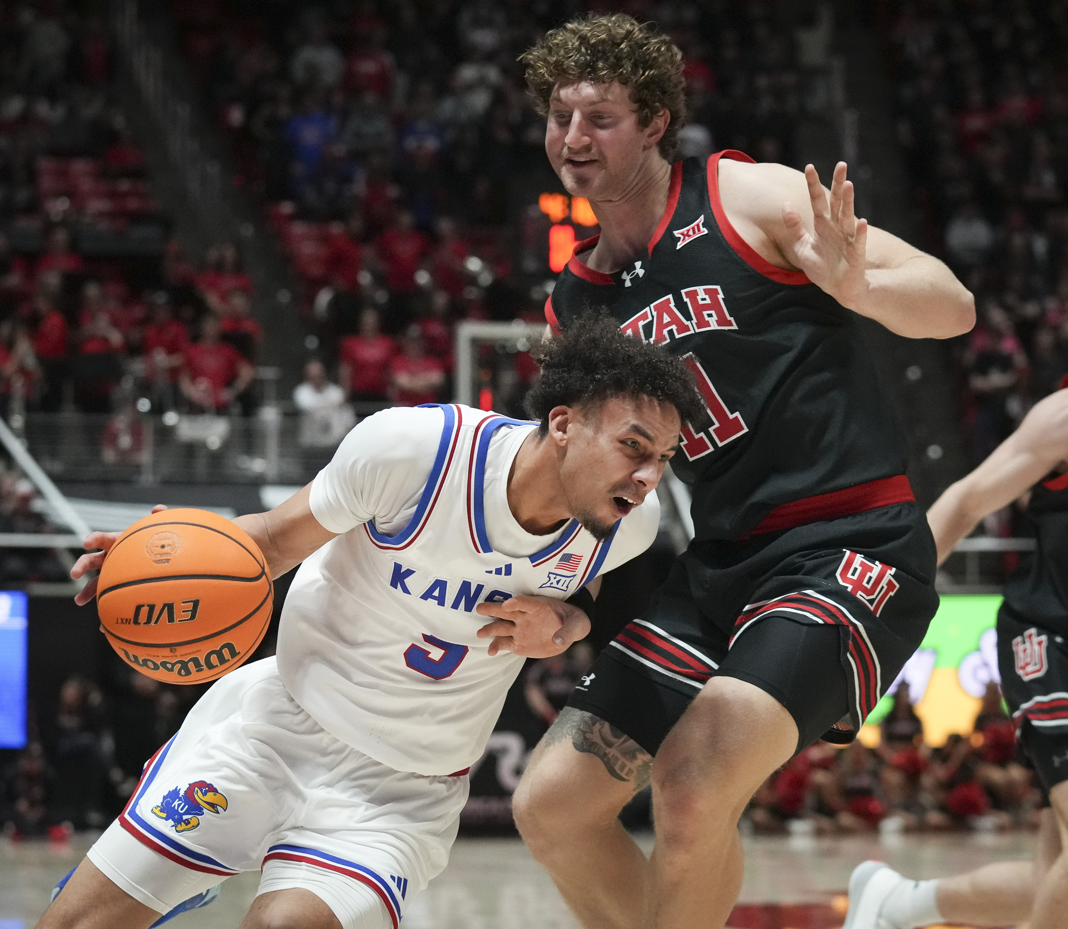 Kansas guard Zeke Mayo (5) drives to the basket as Utah forward Caleb Lohner (11) defends during the first half of an NCAA college basketball game, Saturday, Feb. 15, 2025, in Salt Lake City.