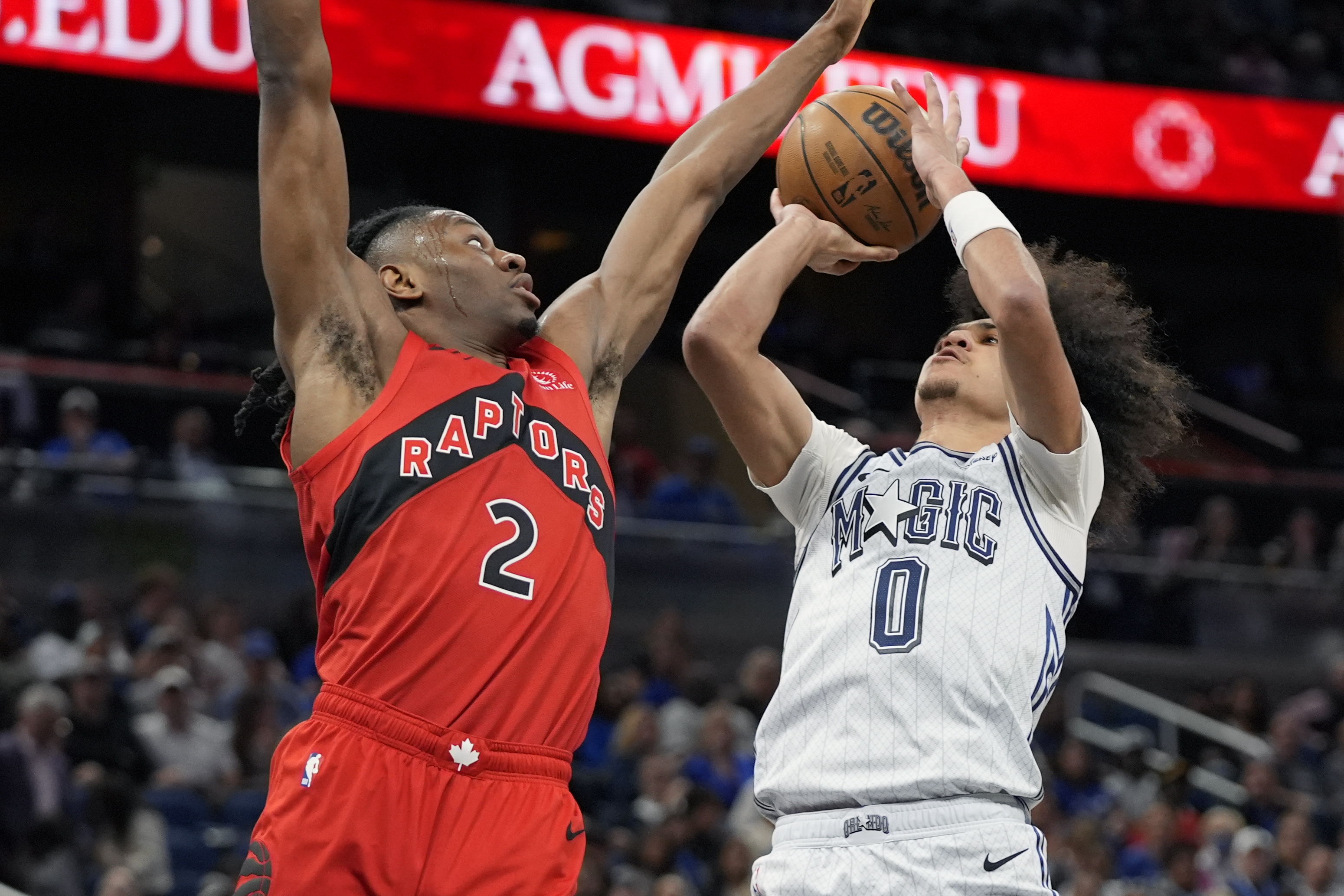 Orlando Magic guard Anthony Black (0) shoots against Toronto Raptors forward Jonathan Mogbo during the first half of an NBA basketball game Sunday, March 2, 2025, in Orlando, Fla.