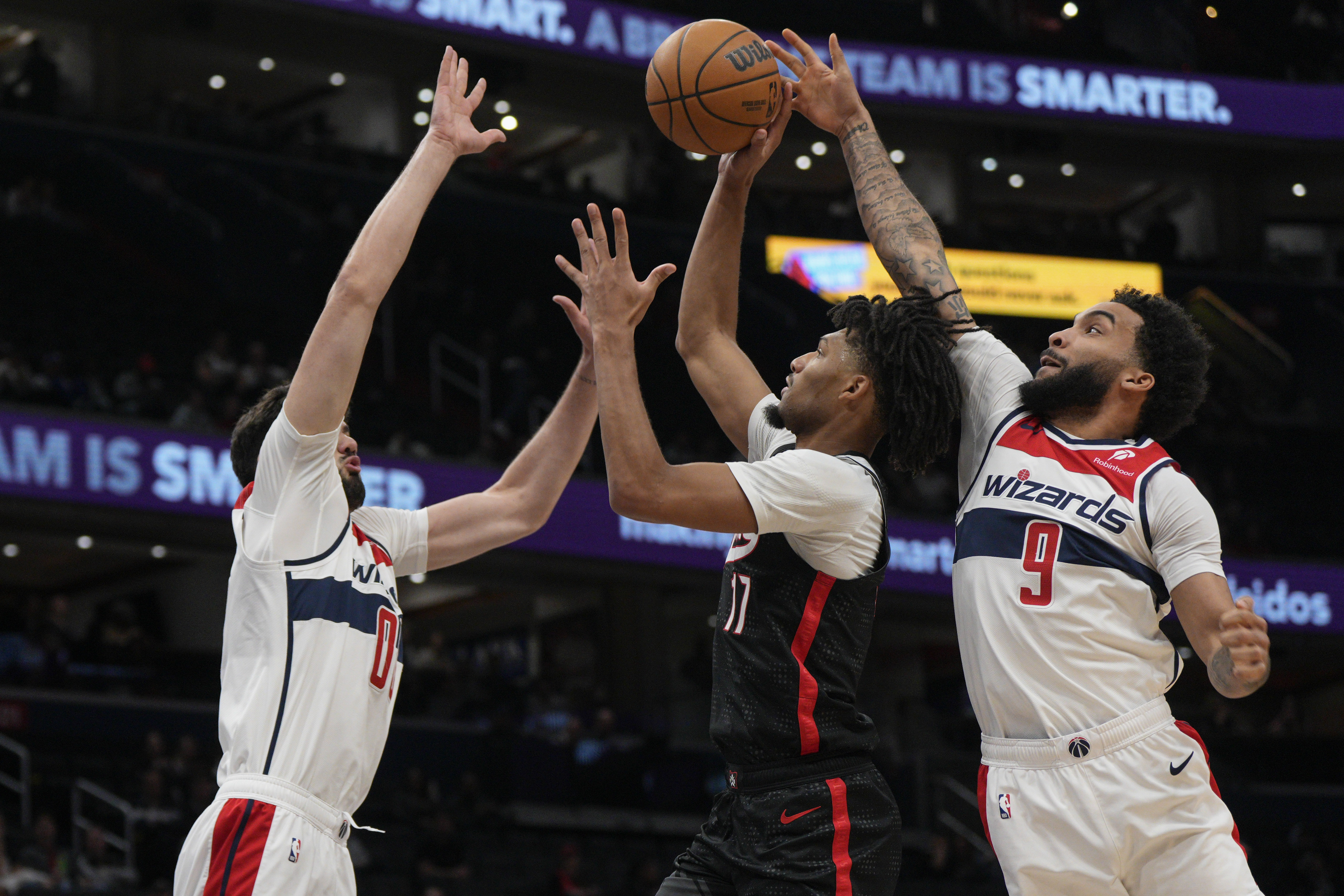 Portland Trail Blazers guard Shaedon Sharpe (17) goes up to shoot as Washington Wizards forwards Tristan Vukcevic (00) and Justin Champagnie (9) defend during the first half of an NBA basketball game, Wednesday, Feb. 26, 2025, in Washington. 