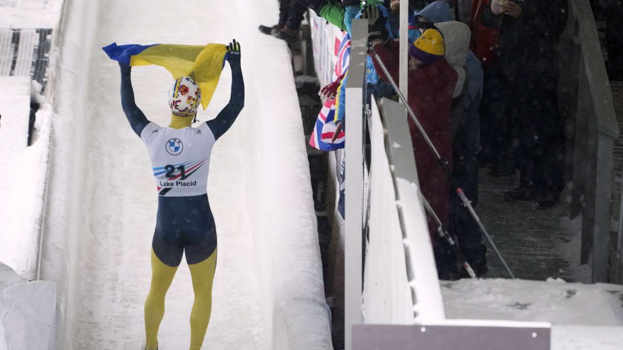 FILE - Valdyslav Heraskevych, of Ukraine, waves a flag as he finishes his second run during the World Cup skeleton competition in Lake Placid, N.Y., Thursday, March 21, 2024.