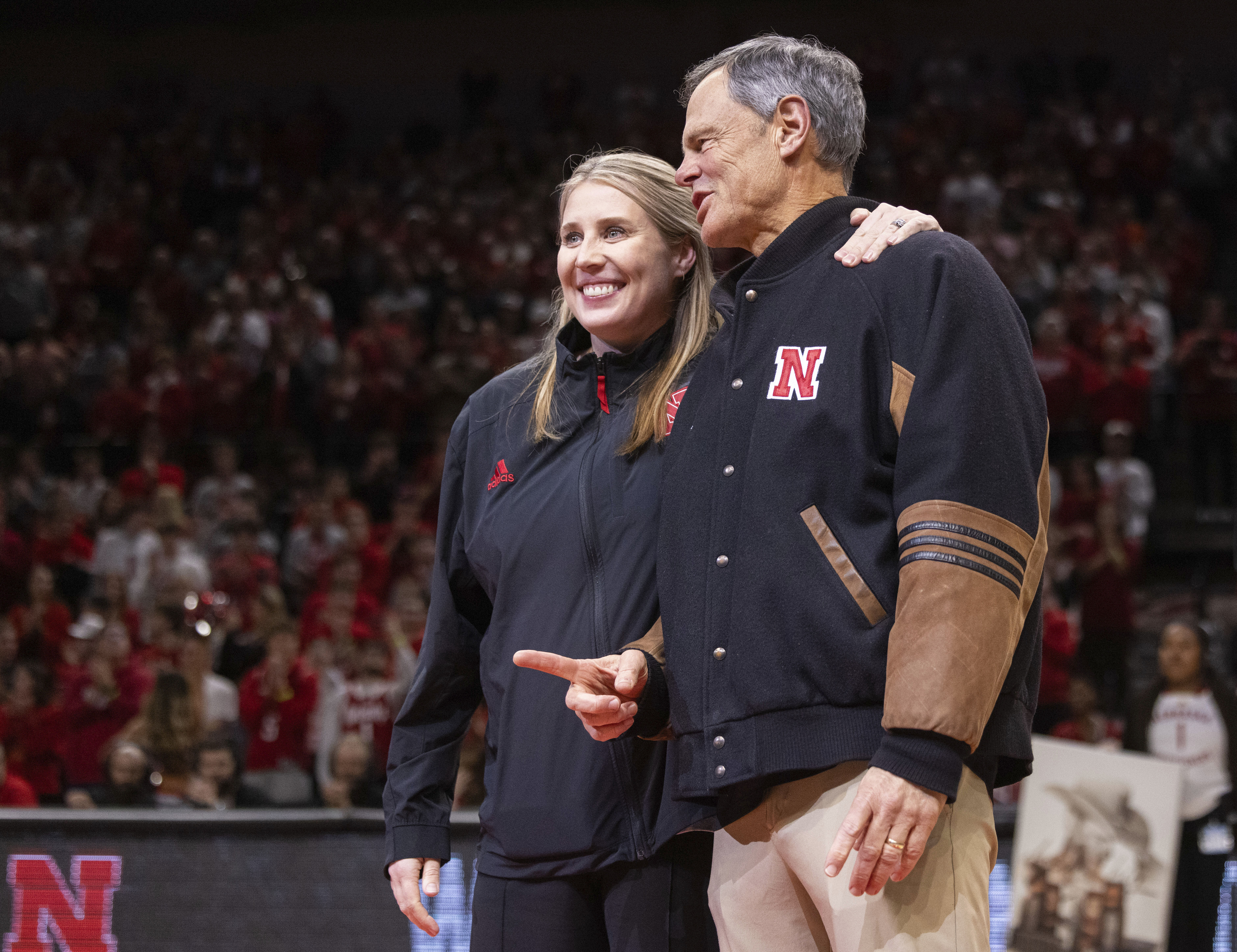 FILE - Newly named Nebraska volleyball head coach Dani Busboom Kelly, left, stands midcourt with retiring volleyball coach John Cook, right, during a timeout acknowledgment as Illinois plays against Nebraska in the first half of an NCAA college basketball game Thursday, Jan. 30, 2025, in Lincoln, Neb. 