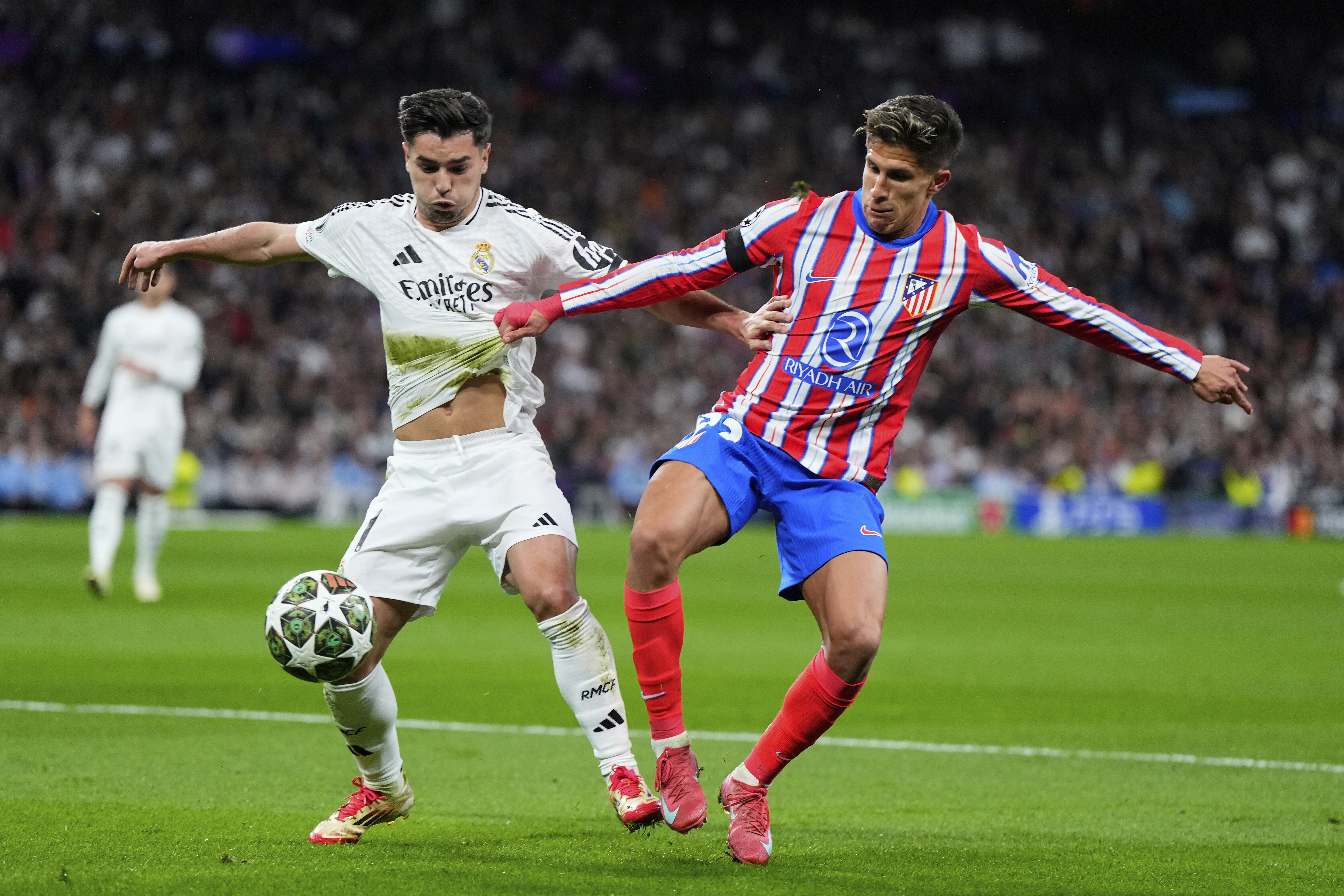 Real Madrid's Brahim Diaz, left, fights for the ball with Atletico Madrid's Reinildo Mandava during the Champions League round of 16 first leg soccer match between Real Madrid and Atletico Madrid at the Bernebeu stadium in Madrid, Spain, Tuesday, March 4, 2025.