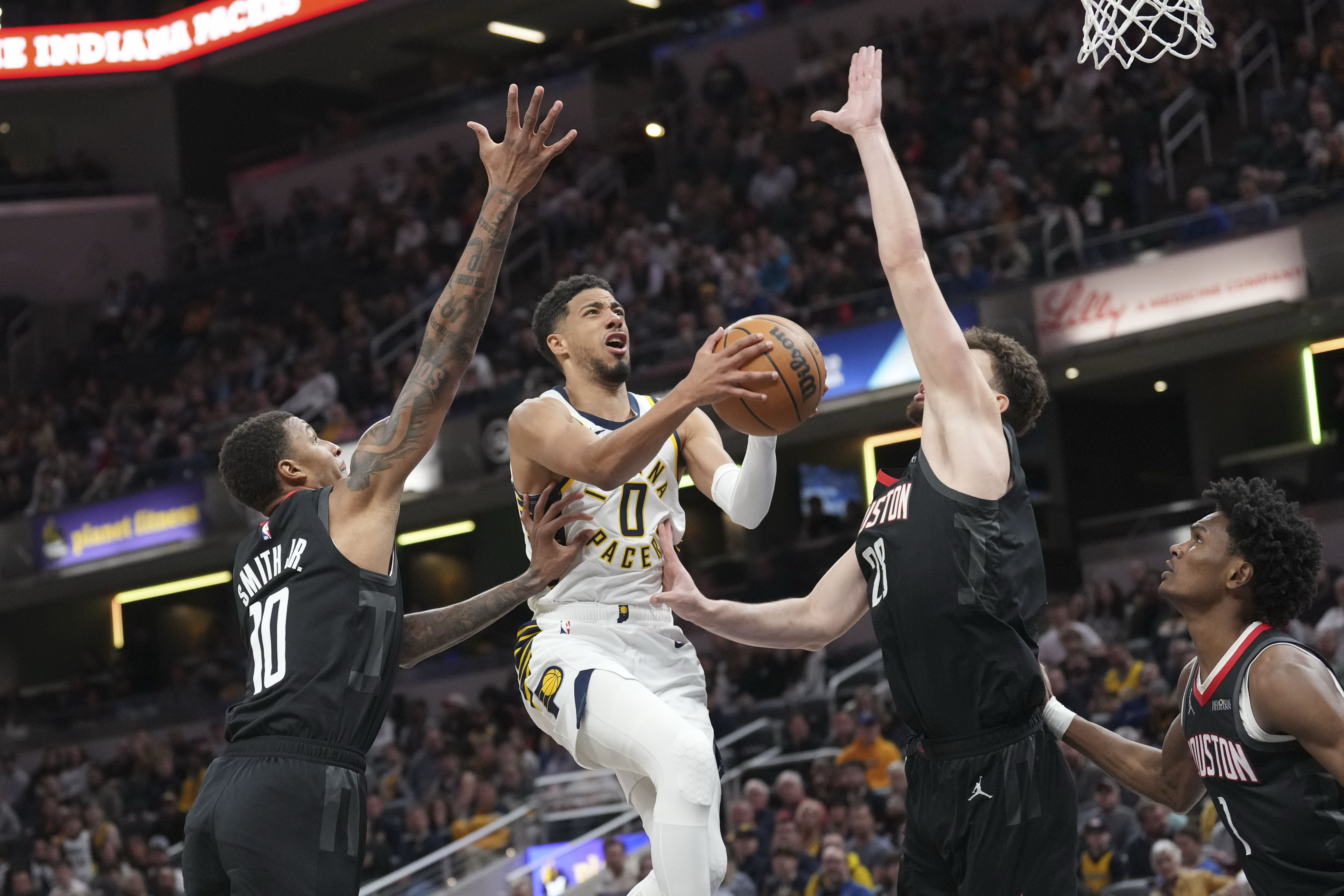 Indiana Pacers guard Tyrese Haliburton, center, shoots between Houston Rockets defenders Jabari Smith Jr., lefrt, and Alperen Sengun during the first half of an NBA basketball game in Indianapolis, Tuesday, March 4, 2025. 