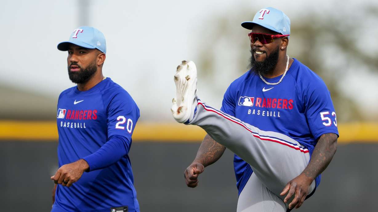 Texas Rangers third baseman Ezequiel Duran (20) and right fielder Adolis Garcia (53) warm up during spring training baseball practice at the team's training facility, Monday, Feb. 17, 2025, in Surprise, Ariz.