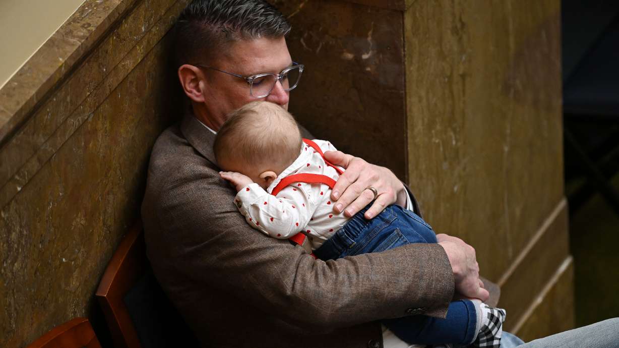 Rep. Jason Thompson, R-River Heights, holds Joey Matthews, son of Rep. Ashlee Matthews, D-West Jordan, in the House on Feb. 14, 2025. The House passed a bill expanding tax credits for Utah employers who provide child care services.