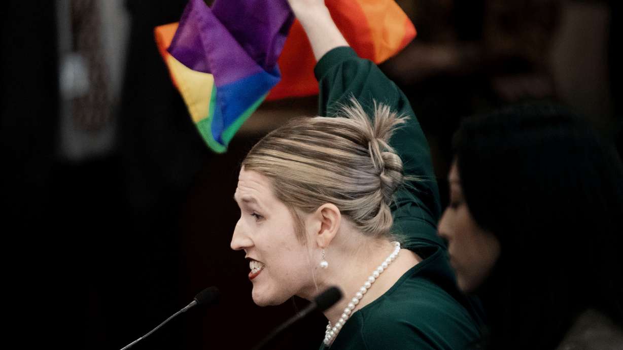 Charlotte Weber displays a pride flag while speaking in opposition to HB77, related to flay displays in schools, at the Capitol in Salt Lake City on Feb. 28.