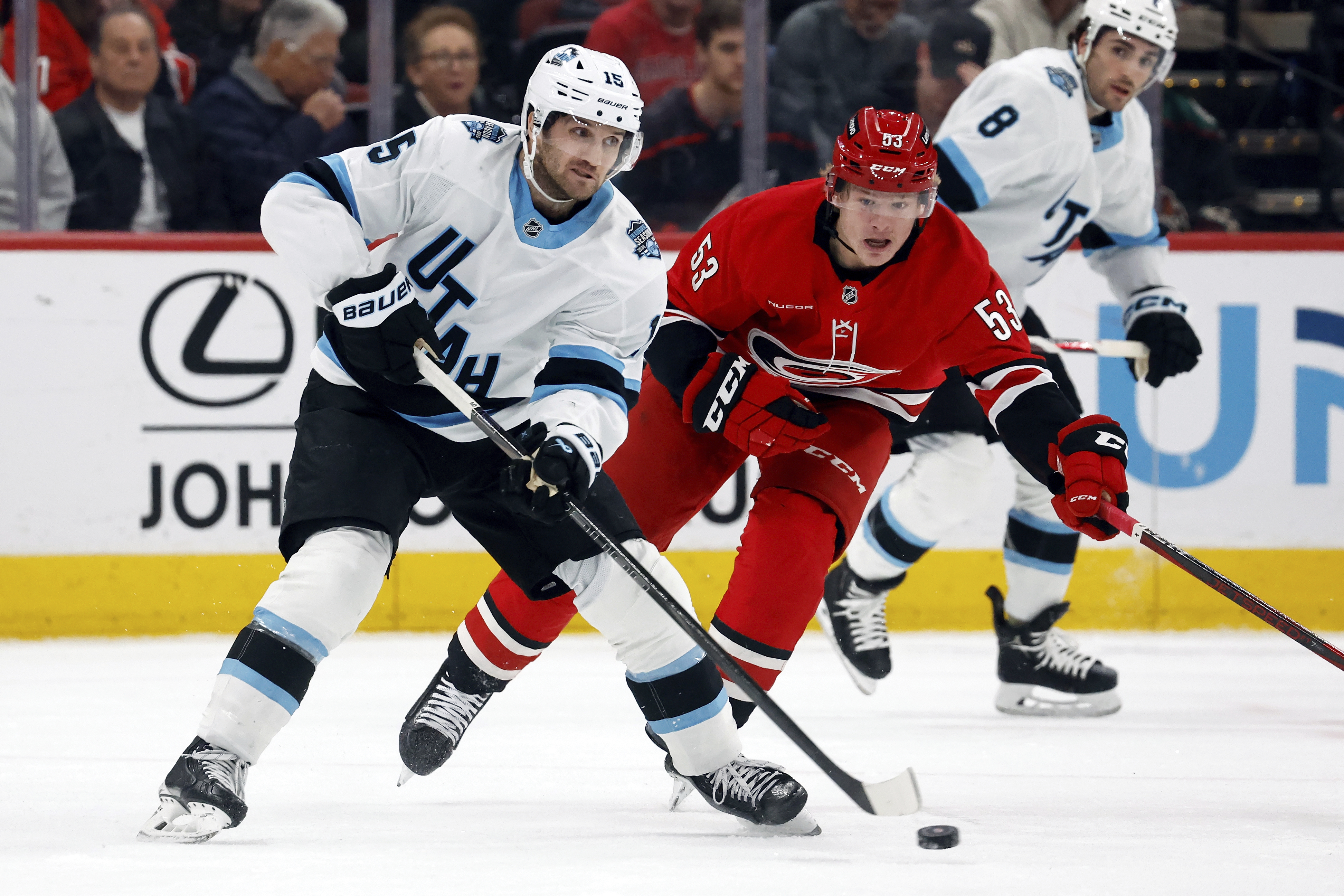 Utah Hockey Club's Alexander Kerfoot (15) moves the puck in front of Carolina Hurricanes' Jackson Blake (53) during the first period of an NHL hockey game in Raleigh, N.C., Saturday, Feb. 8, 2025.