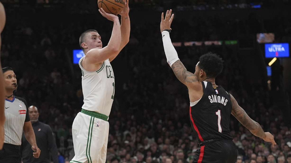 Boston Celtics guard Payton Pritchard, left, takes a 3-pointer over Portland Trail Blazers guard Anfernee Simons (1) during the second half of an NBA basketball game, Wednesday, March 5, 2025, in Boston.
