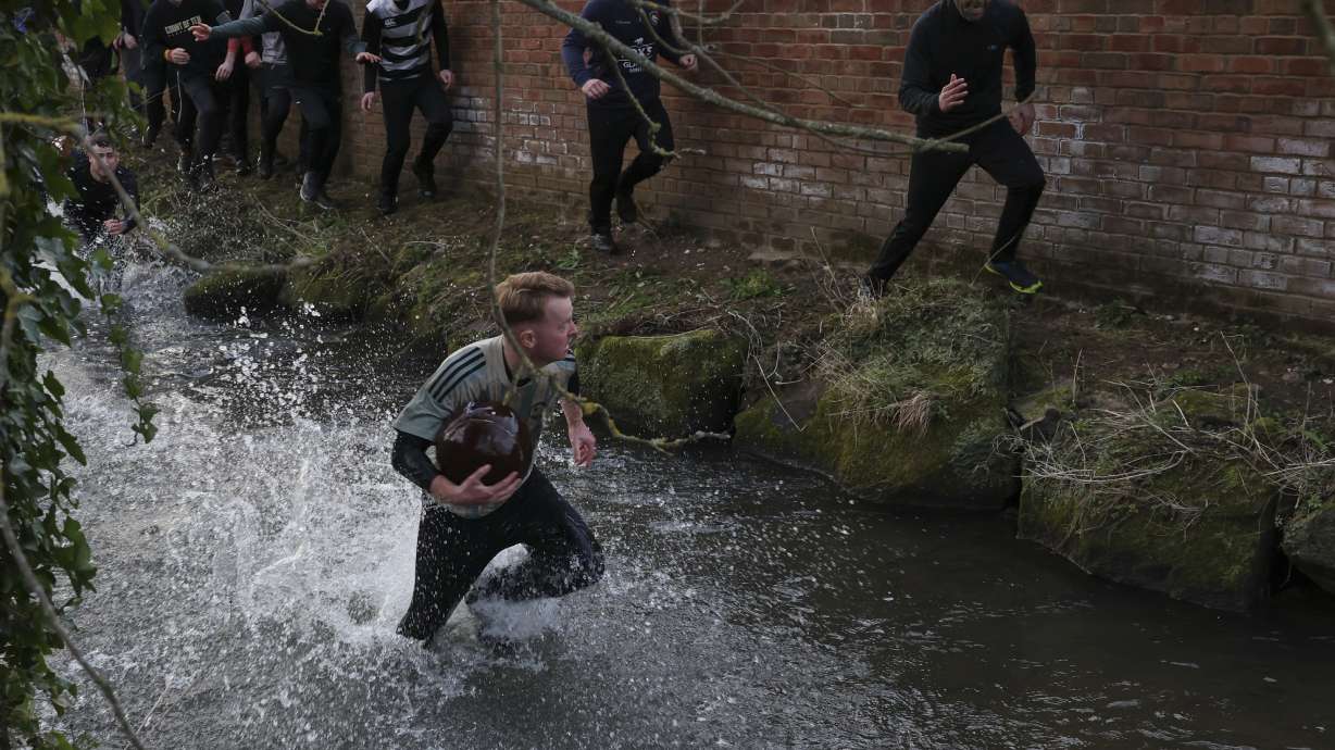 A man runs with the ball in the Henmore Brook during annual Shrovetide medieval soccer match played in Ashbourne, England, Tuesday, March 4, 2025.