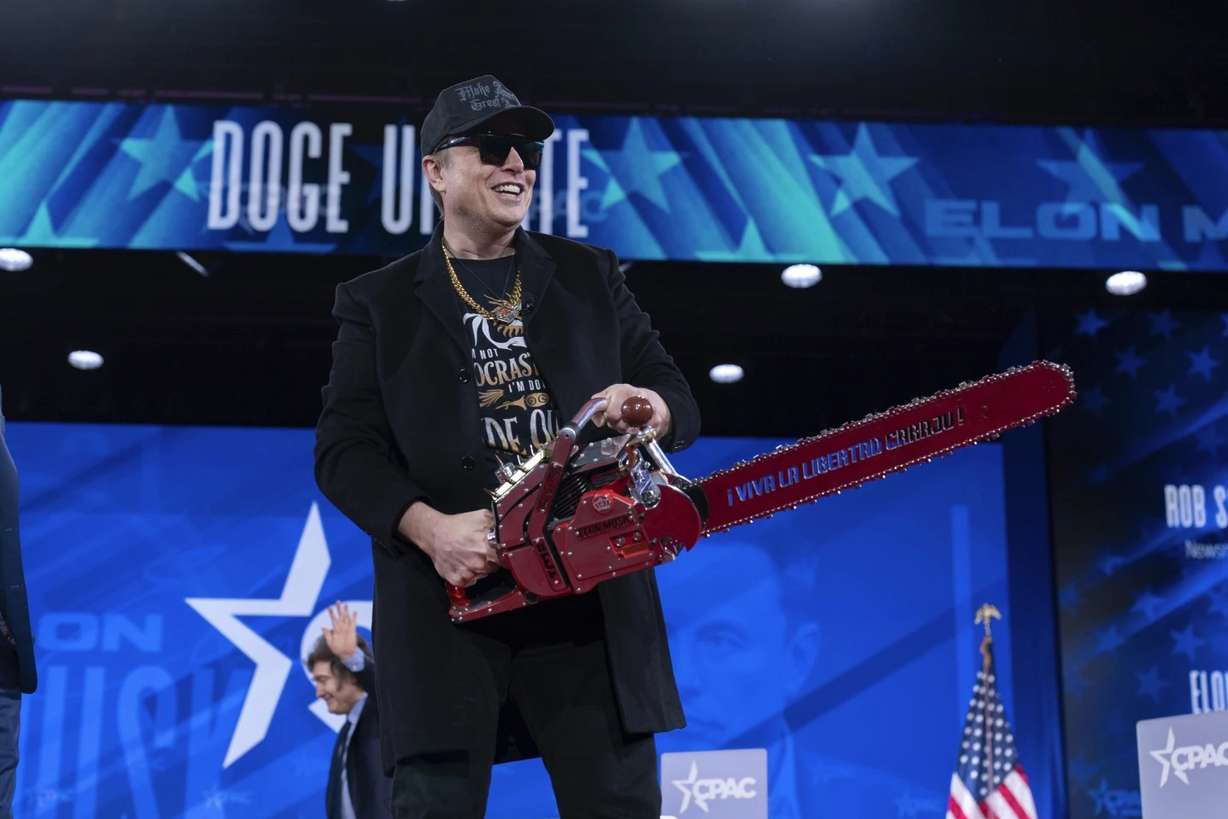 Elon Musk holds a chainsaw as he arrives to speak at the Conservative Political Action Conference at the Gaylord National Resort & Convention Center, Feb. 20, in Oxon Hill, Md.