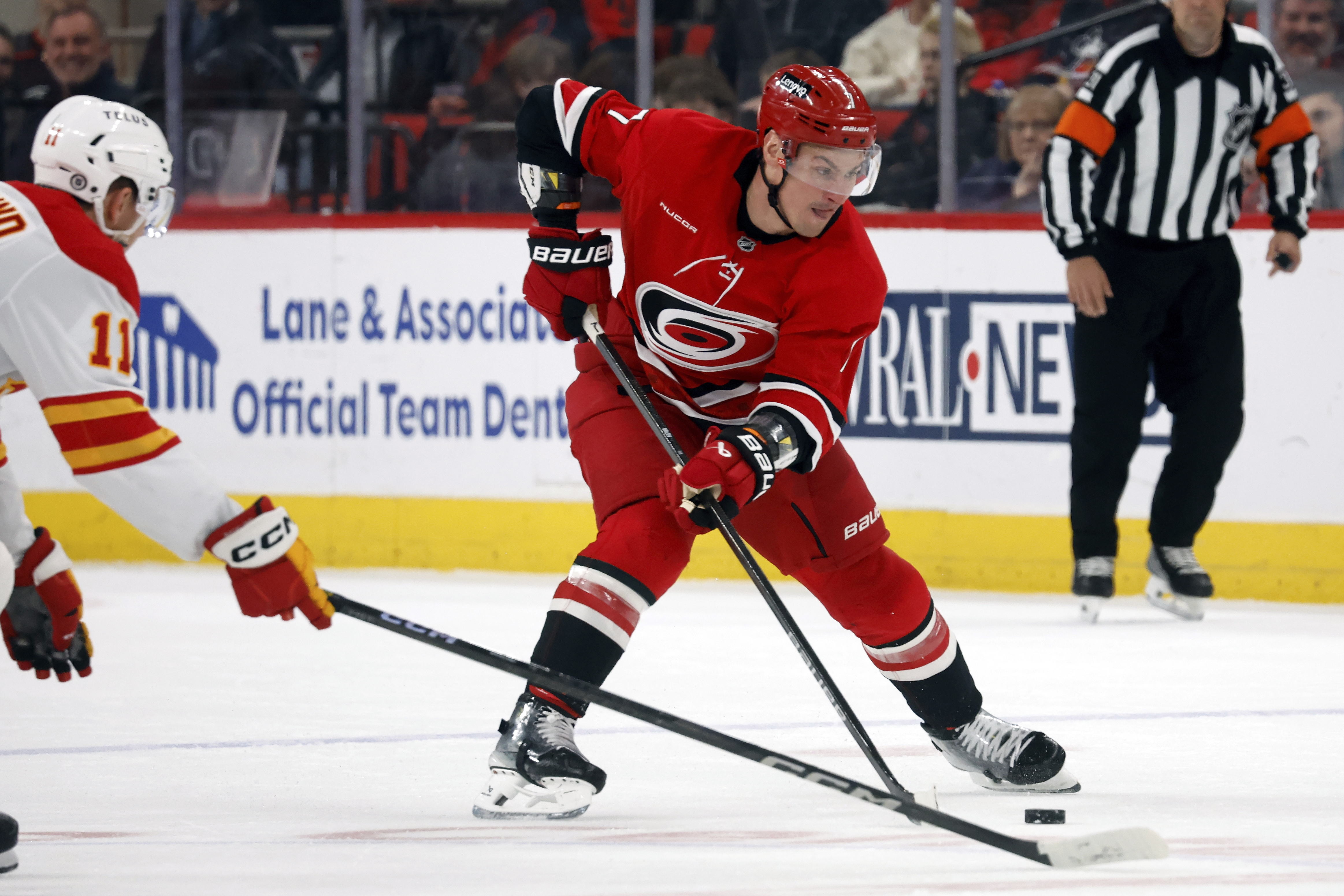 Carolina Hurricanes' Dmitry Orlov controls the puck near Calgary Flames' Mikael Backlund (11) during the second period of an NHL hockey game in Raleigh, N.C., Sunday, March 2, 2025. 