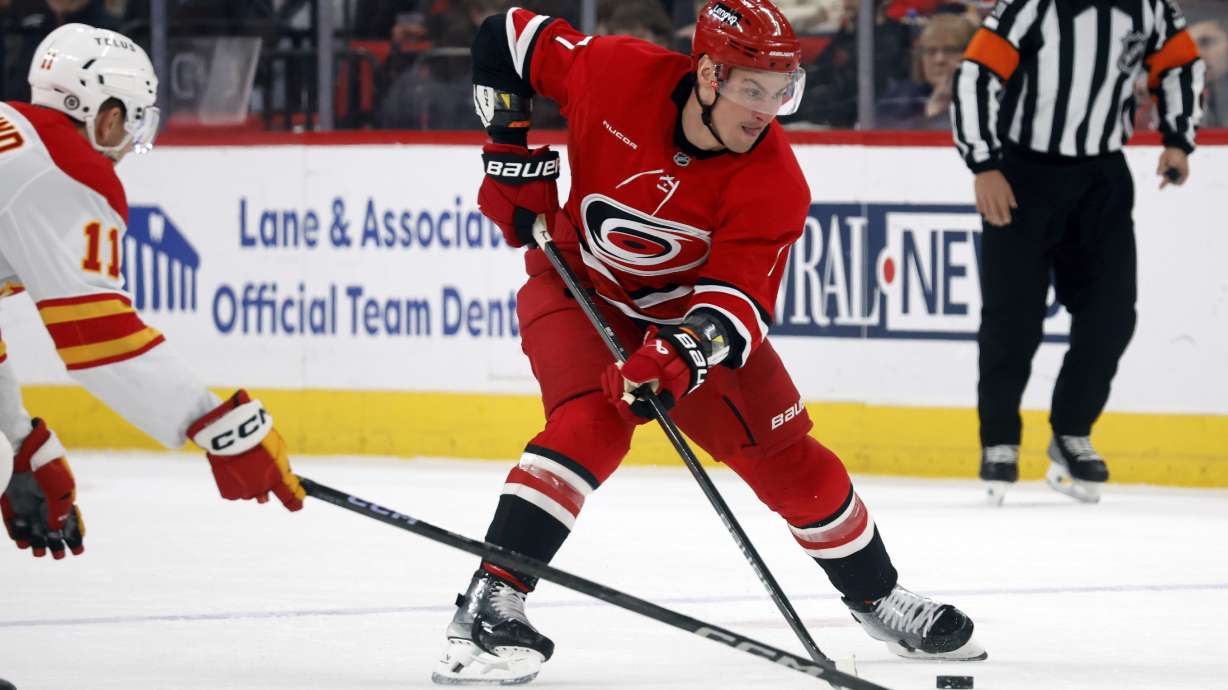 Carolina Hurricanes' Dmitry Orlov controls the puck near Calgary Flames' Mikael Backlund (11) during the second period of an NHL hockey game in Raleigh, N.C., Sunday, March 2, 2025.