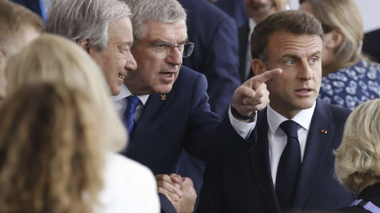 FILE - From left, United Nations' Secretary-General Antonio Guterres, the President of the International Olympic Committee (IOC) Thomas Bach and French President Emmanuel Macron speak, as they arrive, in Paris, France, for the opening ceremony of the 2024 Summer Olympics, Friday, July 26, 2024.