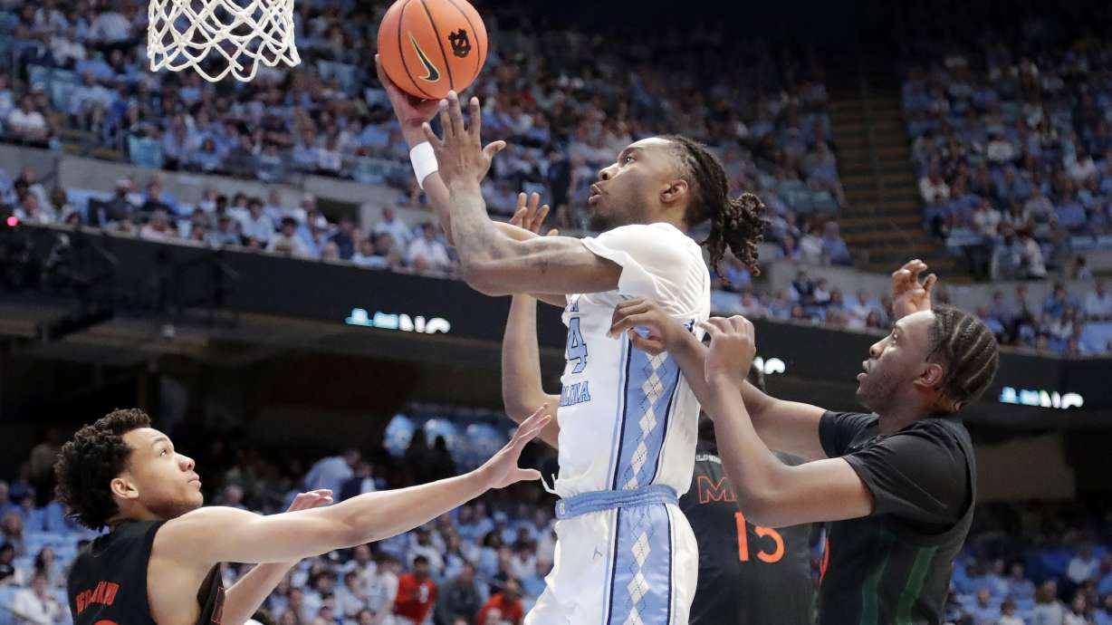 North Carolina forward Jae'Lyn Withers, center, drives between Miami guards Divine Ugochukwu, left, and Paul Djobet, right, during the first half of an NCAA college basketball game Saturday, March 1, 2025, in Chapel Hill, N.C.