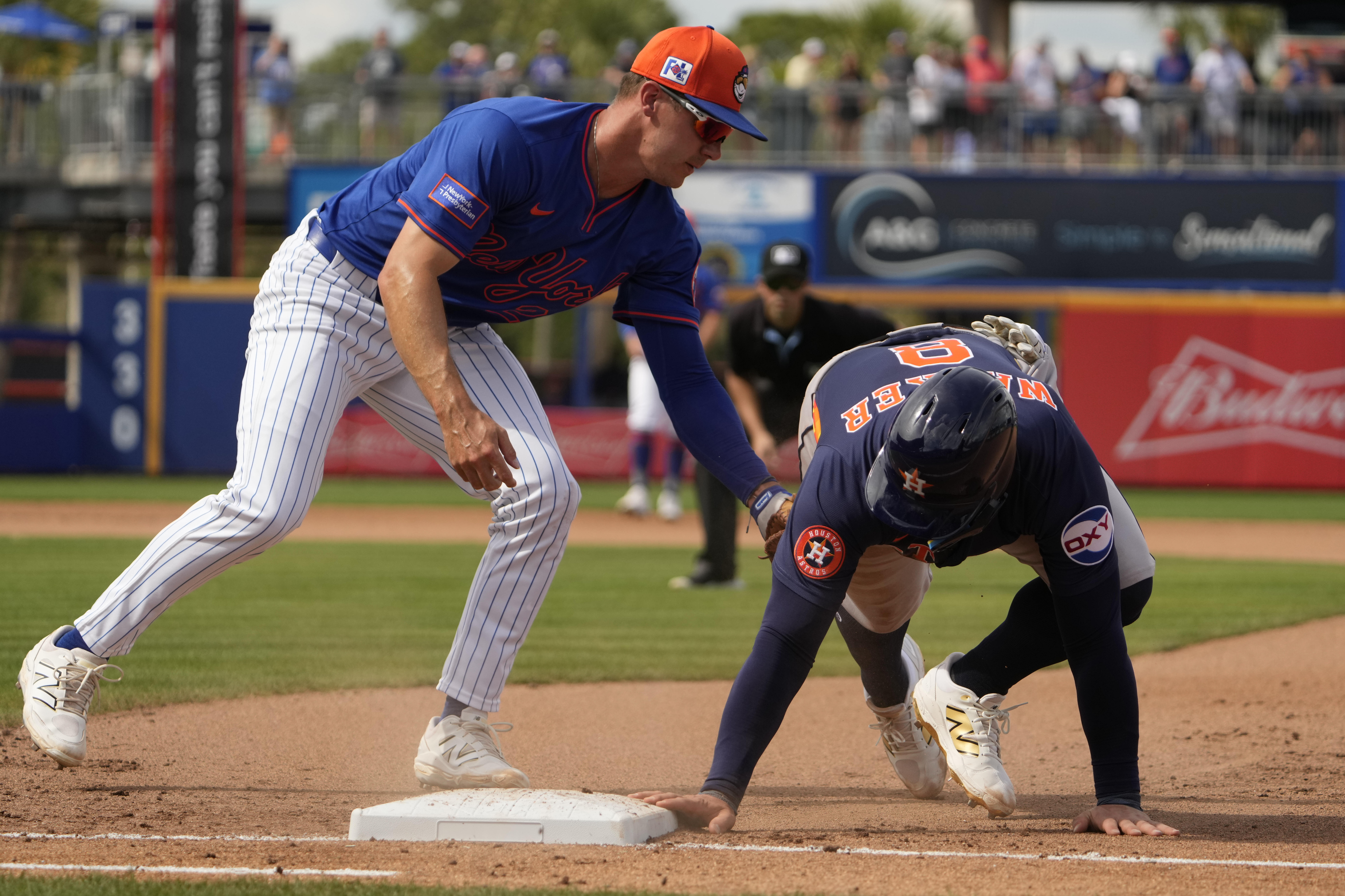 Houston Astros' Christian Walker, right, dives safely back to first ahead of the tag from New York Mets first baseman Jared Young during the fourth inning of a spring training baseball game Thursday, Feb. 27, 2025, in Port St. Lucie, Fla. 