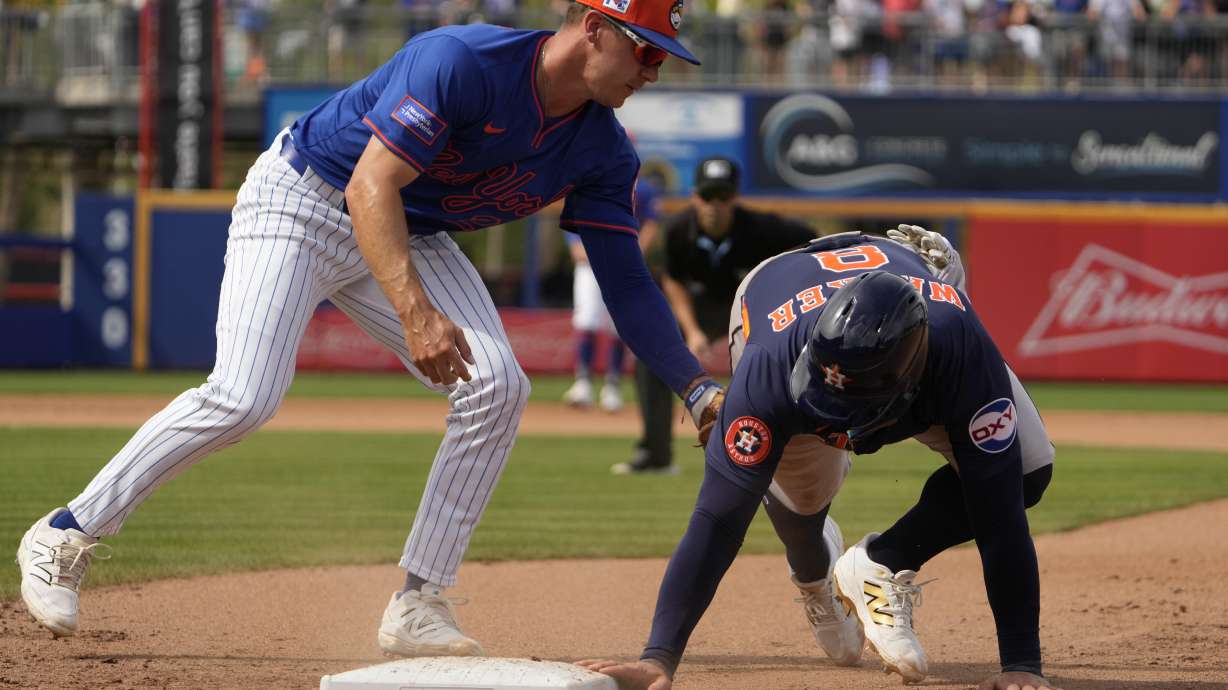 Houston Astros' Christian Walker, right, dives safely back to first ahead of the tag from New York Mets first baseman Jared Young during the fourth inning of a spring training baseball game Thursday, Feb. 27, 2025, in Port St. Lucie, Fla.