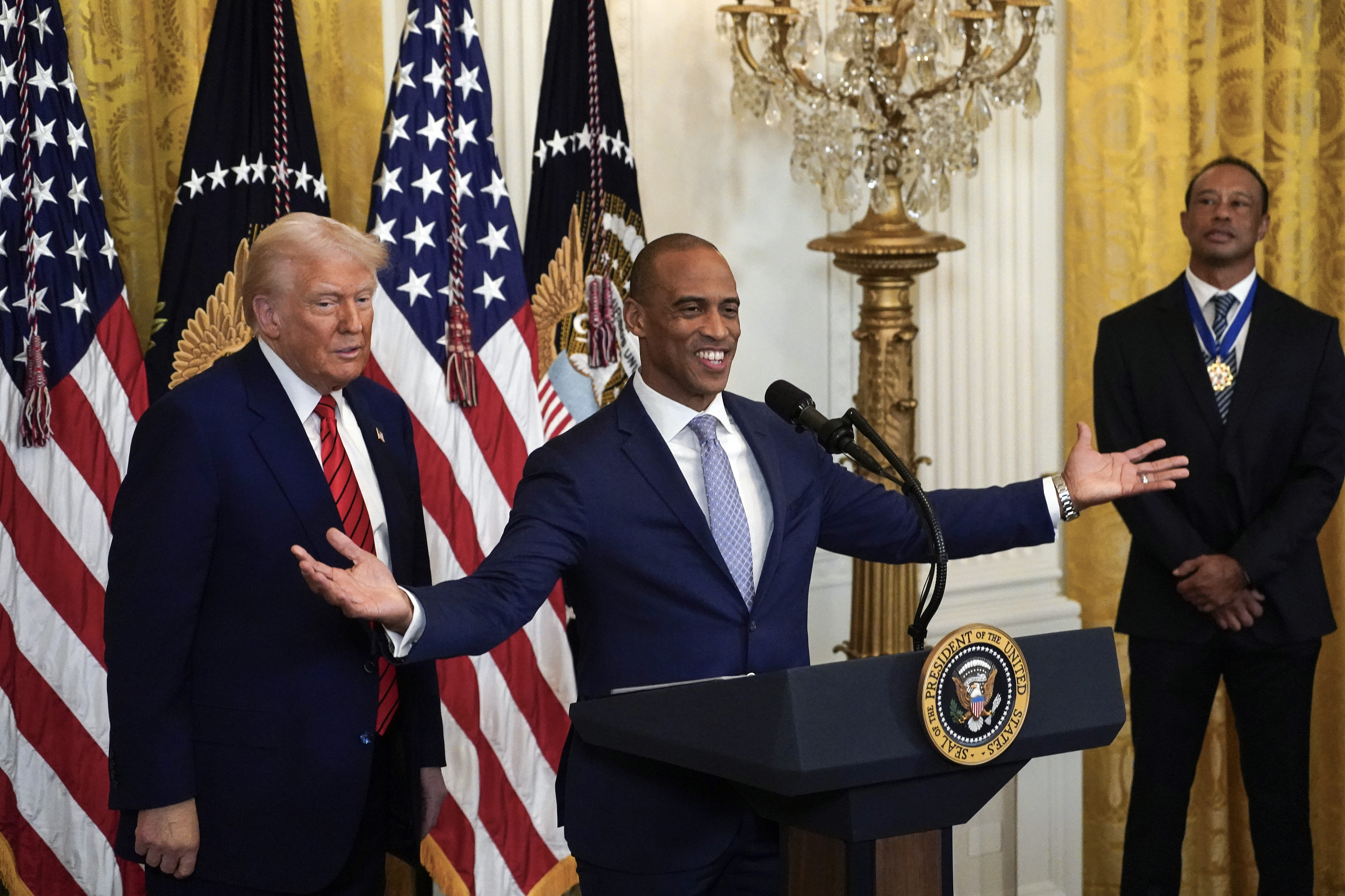 Housing and Urban Development Secretary Scott Turner speaks as President Donald Trump and Tiger Woods listen during a reception for Black History Month in the East Room of the White House Thursday, Feb. 20, 2025.