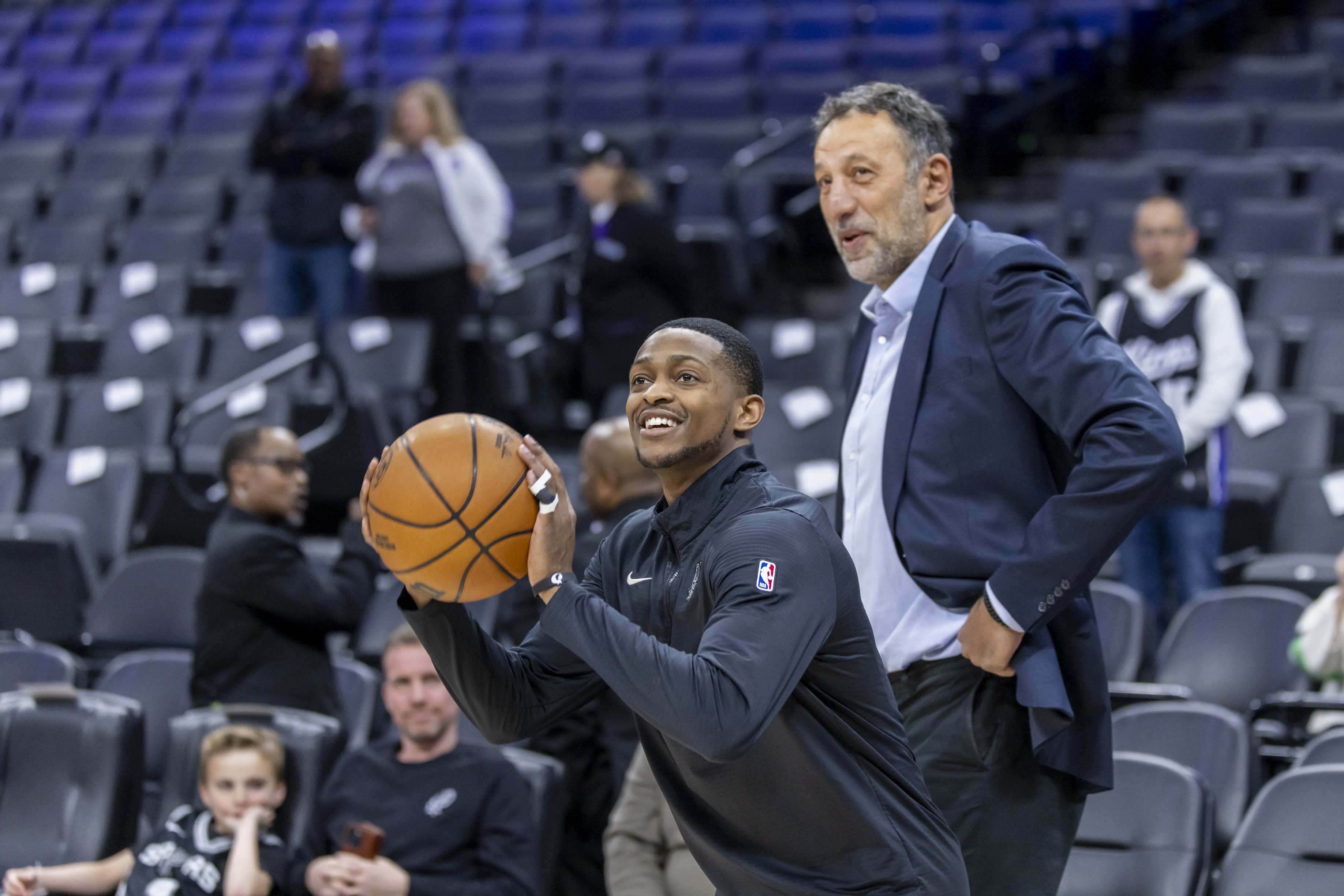 San Antonio Spurs guard De'Aaron Fox, left, warms up as former Sacramento Kings player Vlade Divac, right, looks on before an NBA basketball game against the Kings, Friday, March 7, 2025, in Sacramento, Calif. 