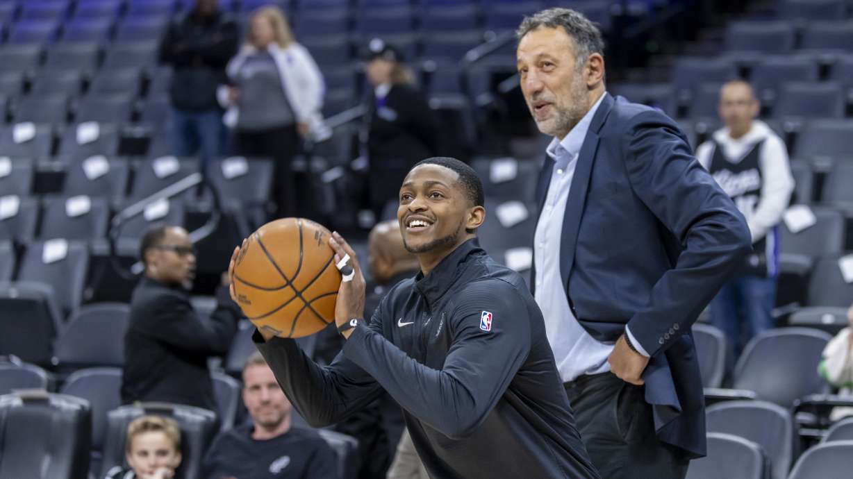San Antonio Spurs guard De'Aaron Fox, left, warms up as former Sacramento Kings player Vlade Divac, right, looks on before an NBA basketball game against the Kings, Friday, March 7, 2025, in Sacramento, Calif.