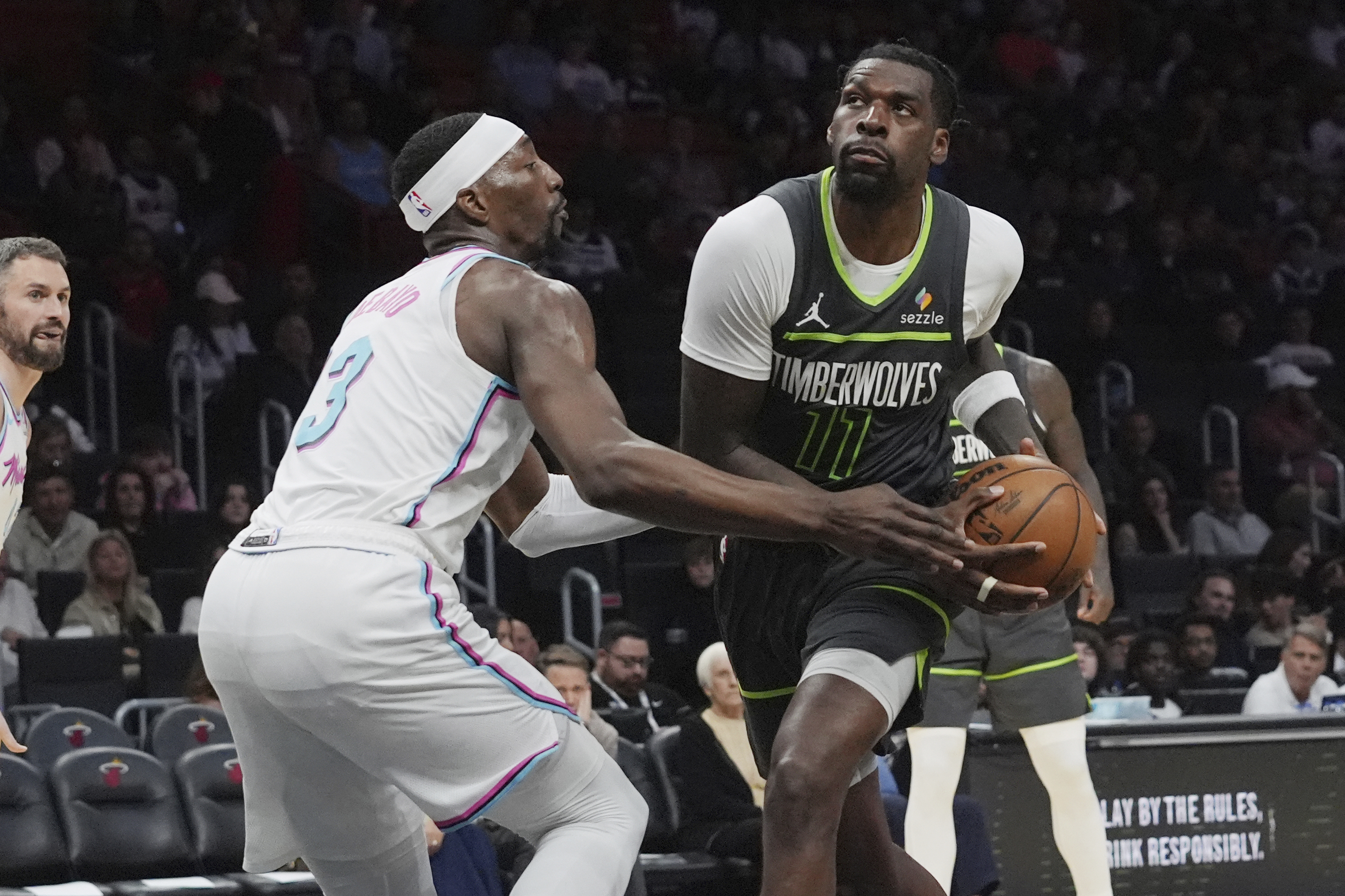 Minnesota Timberwolves center Naz Reid (11) drives to the basket as Miami Heat center Bam Adebayo (13) defends during the second half of an NBA basketball game, Friday, March 7, 2025, in Miami. 
