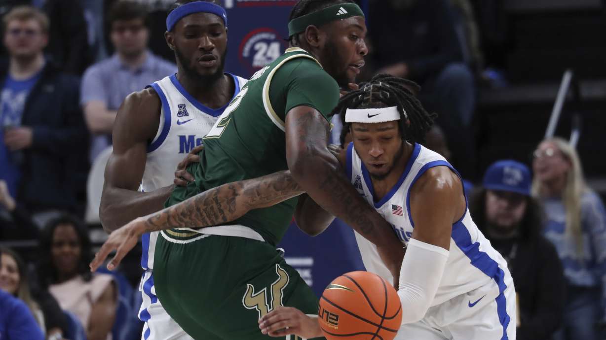 Memphis guard Colby Rogers, right, grabs a steal from South Florida forward Jamille Reynolds (2) with help on defense from Memphis center Moussa Cisse, back left, during the first half of an NCAA college basketball game Friday, March 7, 2025, in Memphis, Tenn.