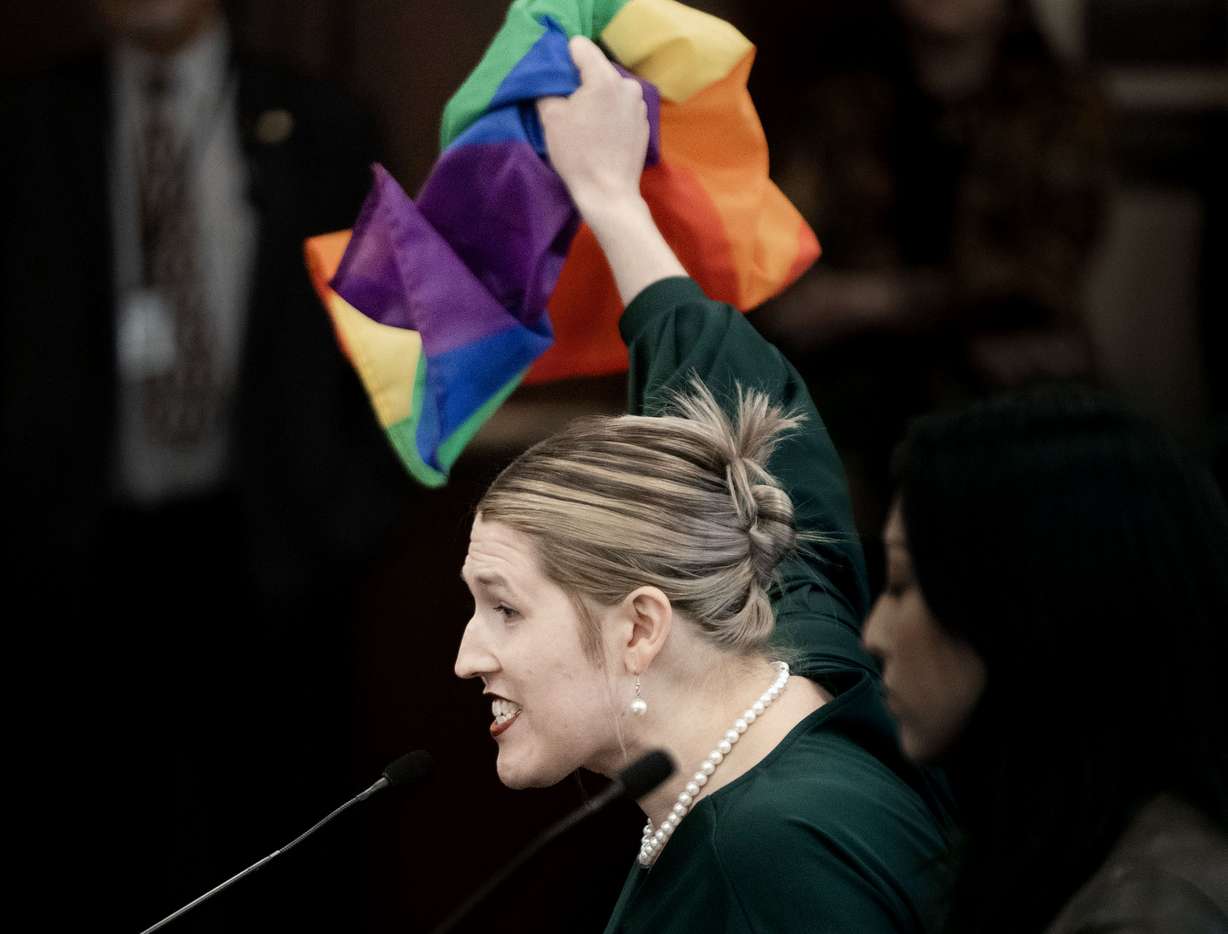 Charlotte Weber displays a pride flag while speaking in opposition to HB77 Flag Display Amendments in a Senate Education Committee meeting at the Capitol in Salt Lake City on Friday, Feb. 28, 2025.