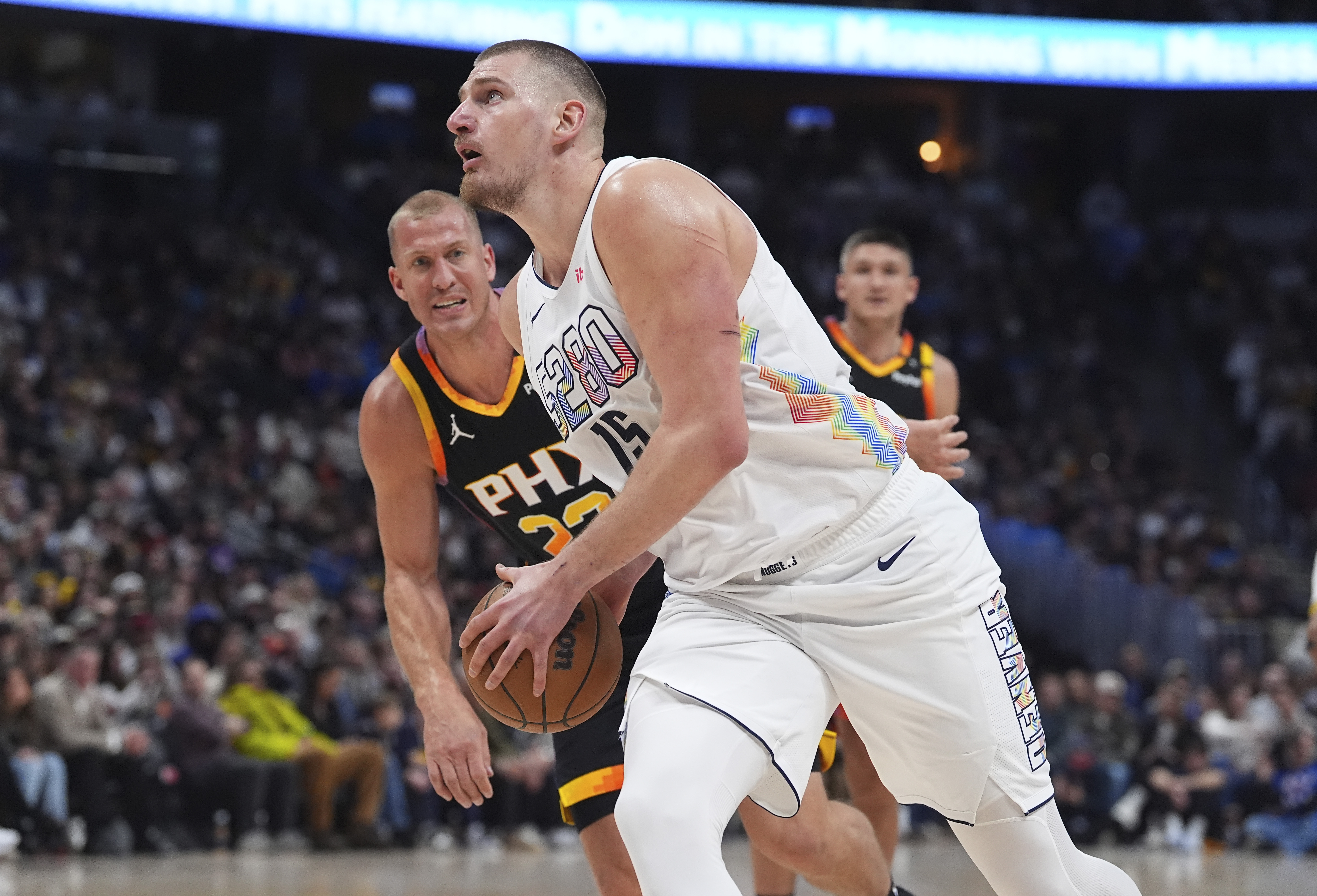 Denver Nuggets center Nikola Jokic, front, drives past Phoenix Suns center Mason Plumlee in the first half of an NBA basketball game Friday, March 7, 2025, in Denver. 