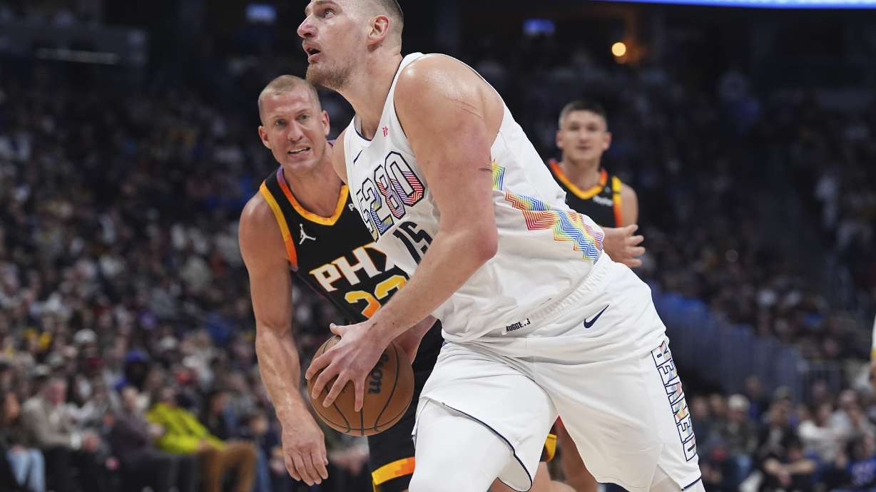 Denver Nuggets center Nikola Jokic, front, drives past Phoenix Suns center Mason Plumlee in the first half of an NBA basketball game Friday, March 7, 2025, in Denver.