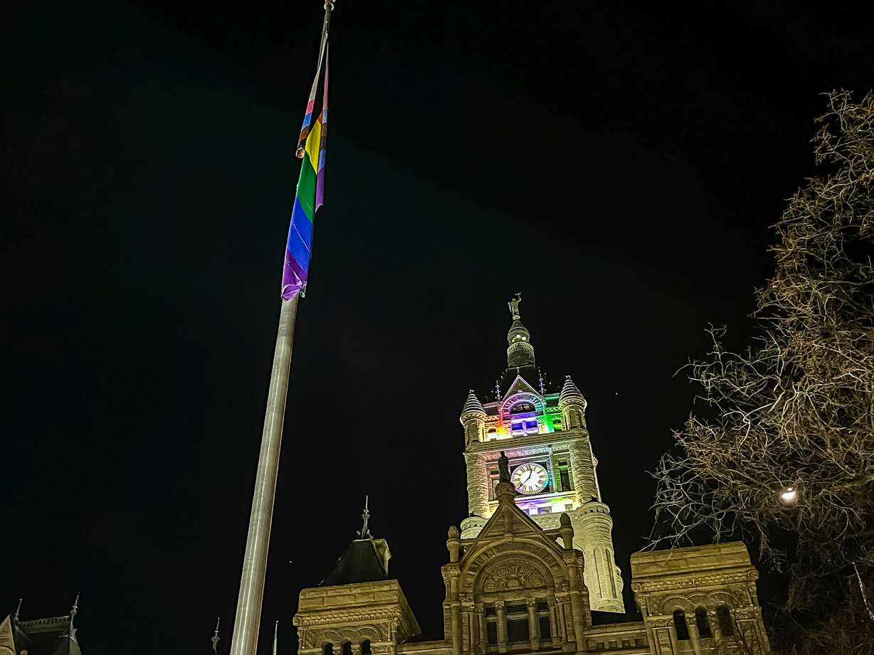 A progress pride flag flies outside of the Salt Lake City-County building in Salt Lake City early Saturday morning, which is also lit up in rainbow colors, minutes after the 2025 legislative session ended. HB77, which was approved by the Utah Legislature this week, would ban Salt Lake City and other cities from displaying the flag or colors once it's in law.