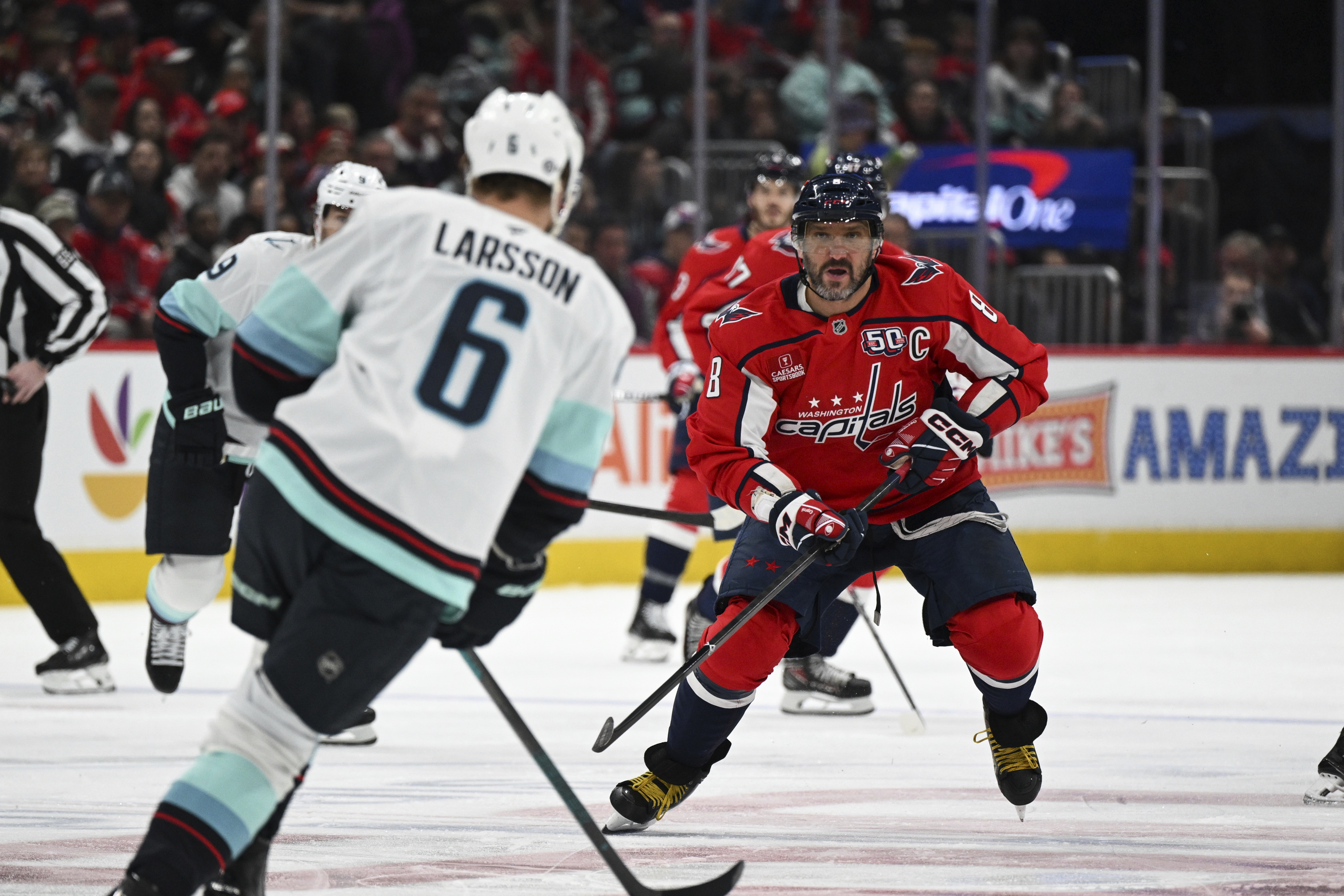 Washington Capitals left wing Alex Ovechkin (8) gets back on defense as Seattle Kraken defenseman Adam Larsson (6) skates with the puck during the first period of an NHL hockey game, Sunday, March 9, 2025, in Washington.