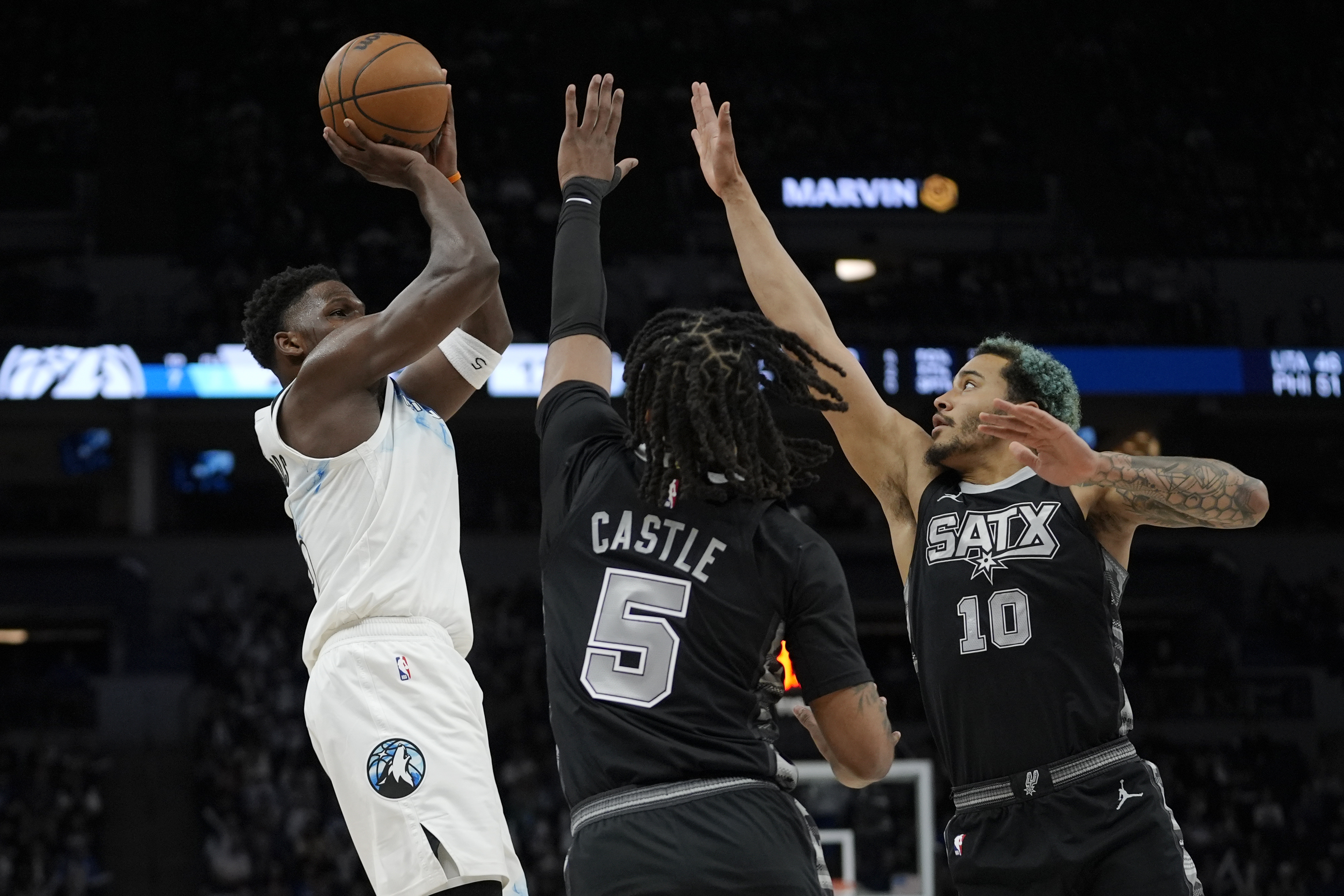 Minnesota Timberwolves guard Anthony Edwards, left, looks to shoot over San Antonio Spurs guard Stephon Castle (5) and forward Jeremy Sochan (10) during the first half of an NBA basketball game, Sunday, March 9, 2025, in Minneapolis. 