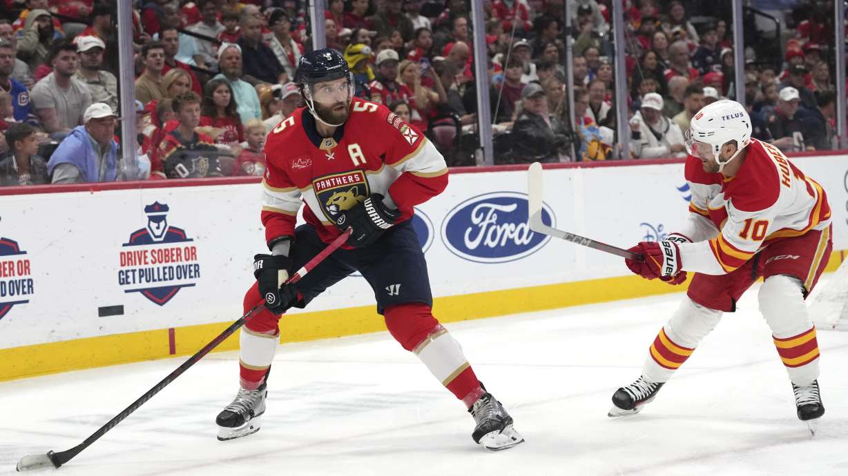 Florida Panthers defenseman Aaron Ekblad (5) skates with the puck as Calgary Flames left wing Jonathan Huberdeau (10) defends during the first period of an NHL hockey game, Saturday, March 1, 2025, in Sunrise, Fla.