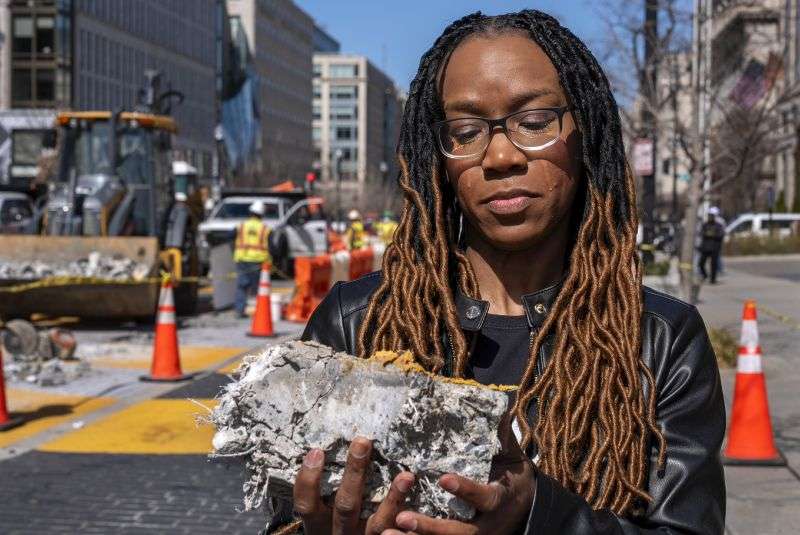 Tears roll down the face of Starlette Thomas, of Bowie, Md., as she holds a chunk of pavement from the Black Lives Matter mural, Monday, as the mural begins to be demolished in Washington."