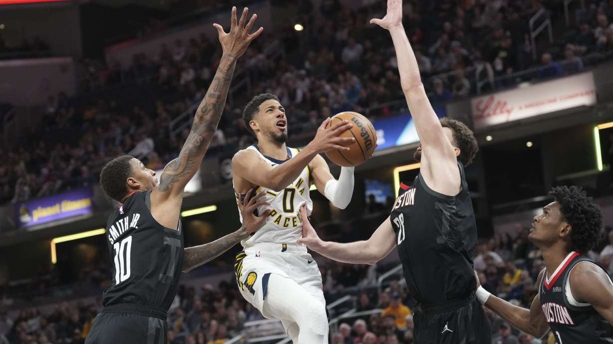 Indiana Pacers guard Tyrese Haliburton, center, shoots between Houston Rockets defenders Jabari Smith Jr., lefrt, and Alperen Sengun during the first half of an NBA basketball game in Indianapolis, Tuesday, March 4, 2025.