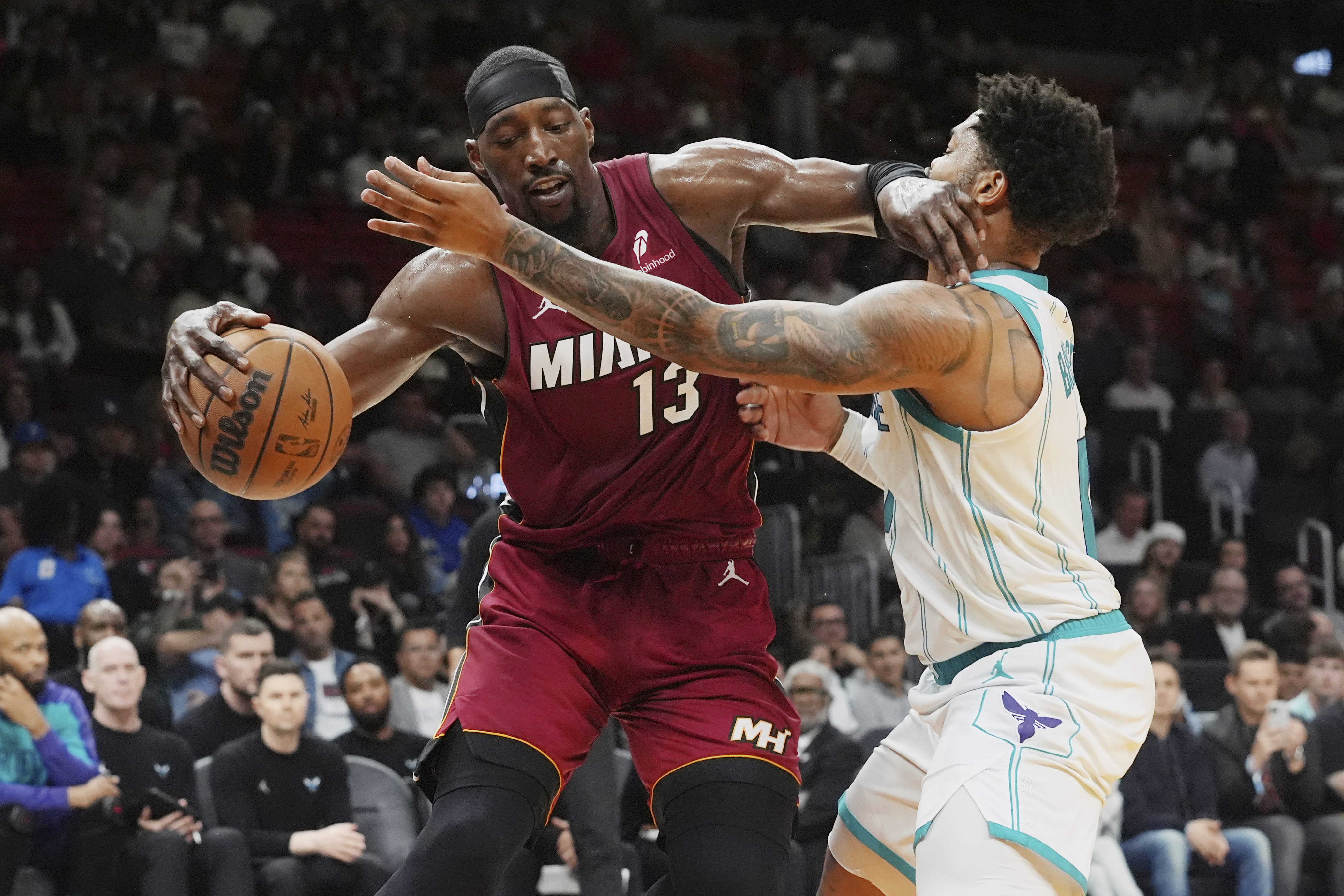 Miami Heat center Bam Adebayo (13) dribbles the ball as Charlotte Hornets forward Miles Bridges (0) defends during the first half of an NBA basketball game, Monday, March 10, 2025, in Miami. 