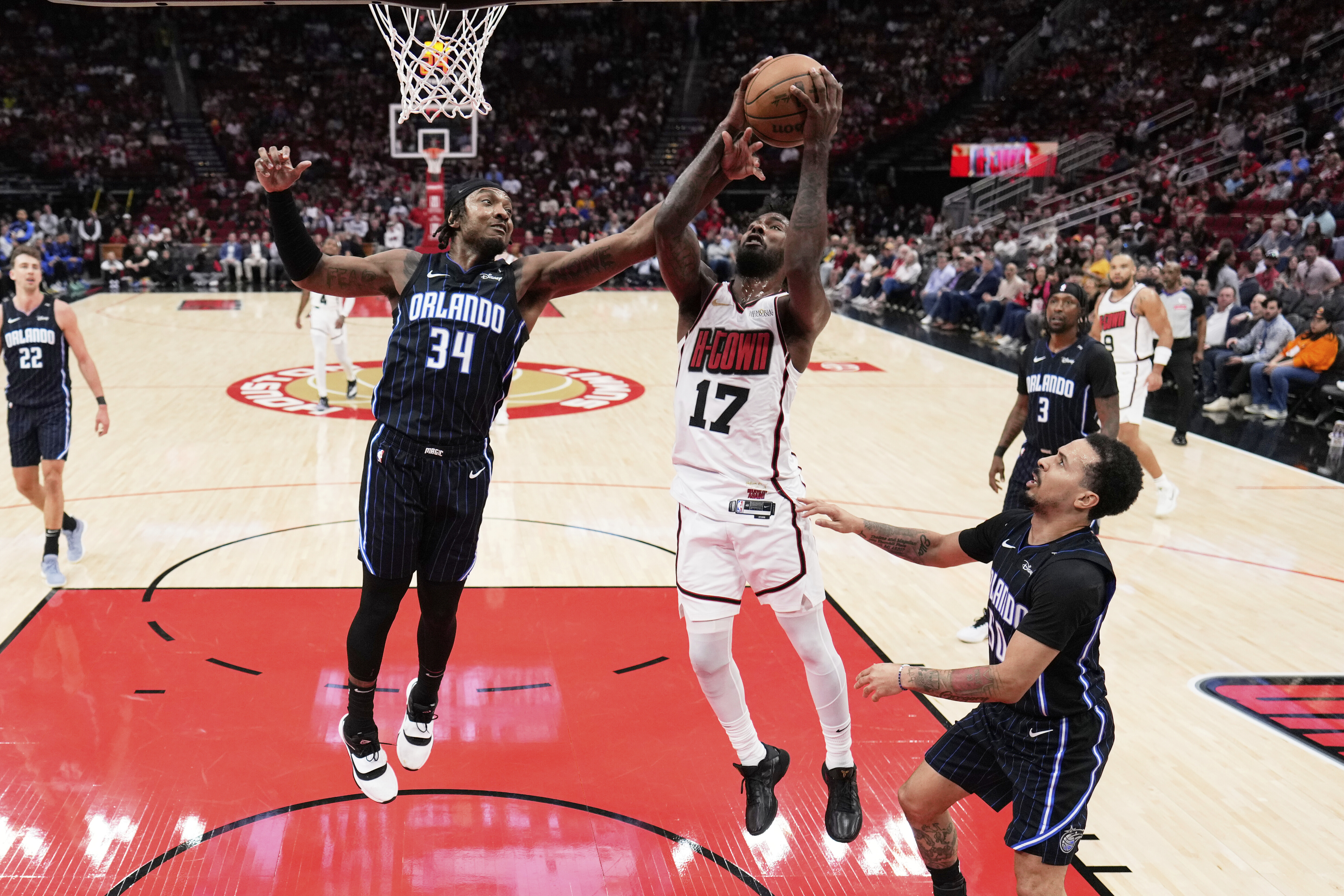 Houston Rockets' Tari Eason (17) and Orlando Magic's Wendell Carter Jr. (34) reach for a rebound during the first half of an NBA basketball game Monday, March 10, 2025, in Houston. 