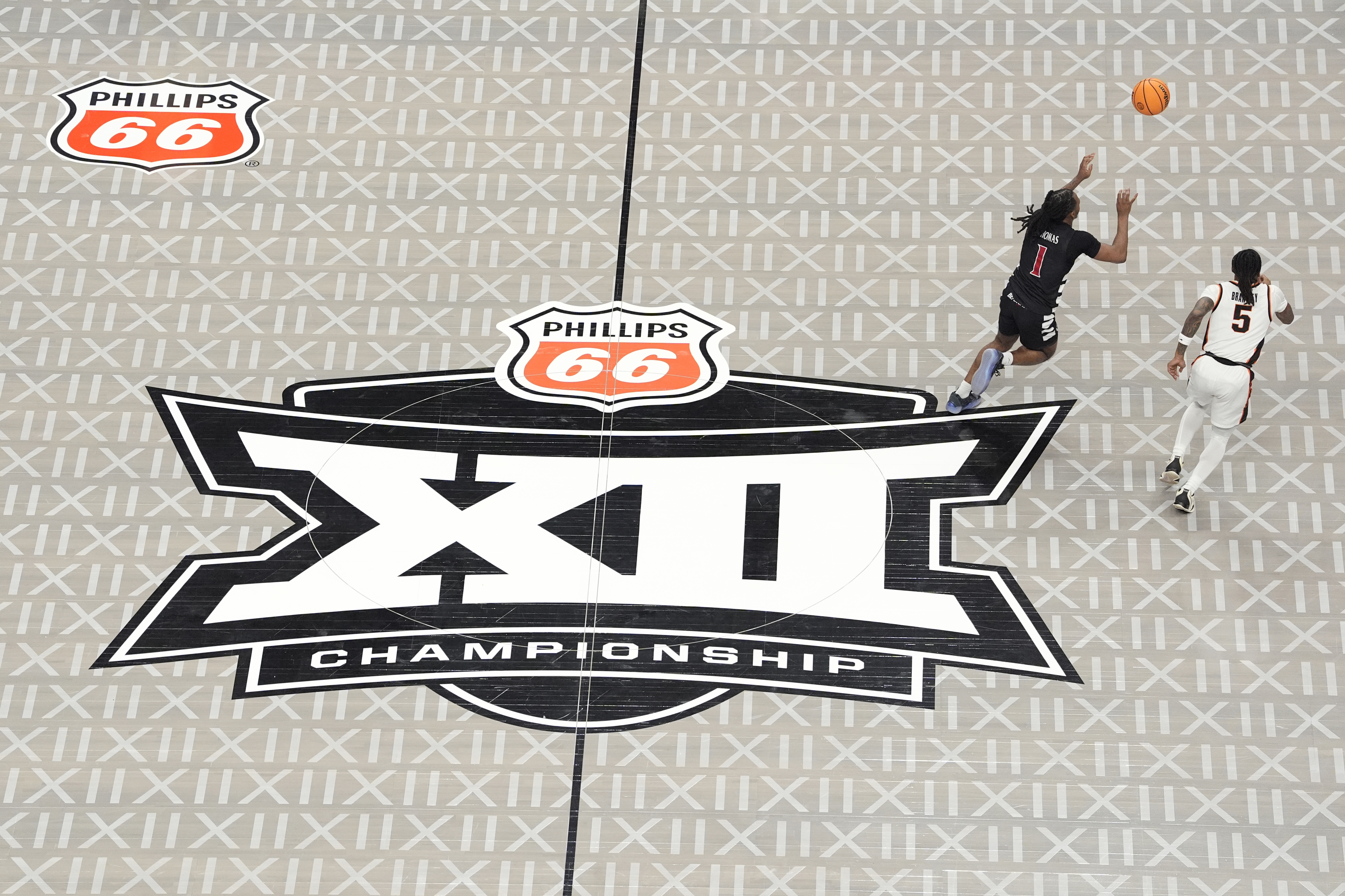 Cincinnati's Day Day Thomas (1) reaches for the ball along with Oklahoma State's Khalil Brantley (5) as the Big 12 logo is seen on the court during the second half of an NCAA college basketball game in the first round of the Big 12 Conference tournament, Tuesday, March 11, 2025, in Kansas City, Mo. 