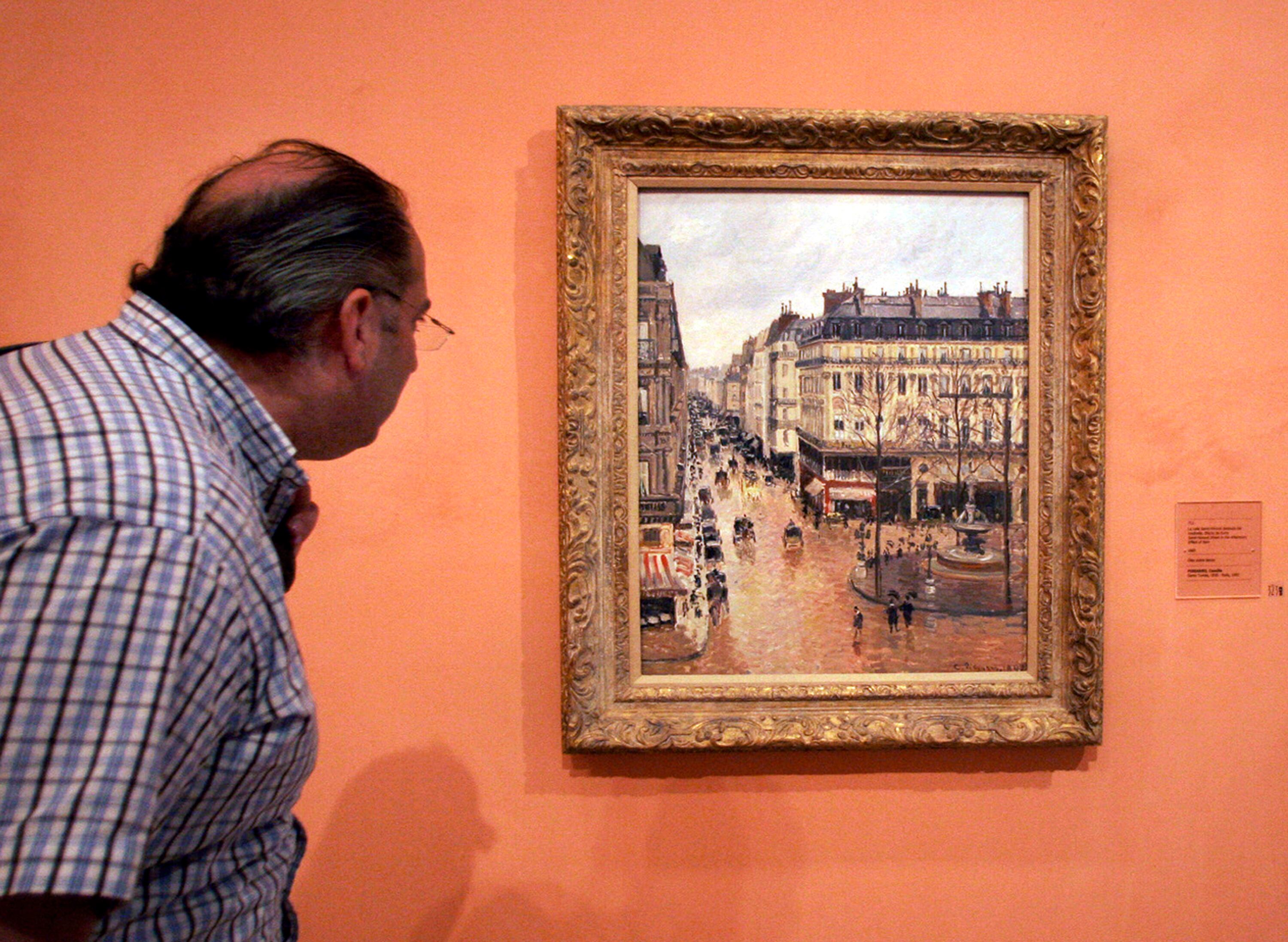 This May 12, 2005, file photo shows an unidentified visitor viewing the Impressionist painting called "Rue St.-Honore, Apres-Midi, Effet de Pluie," in Madrid. The Supreme Court is hearing the case about the stolen artwork.